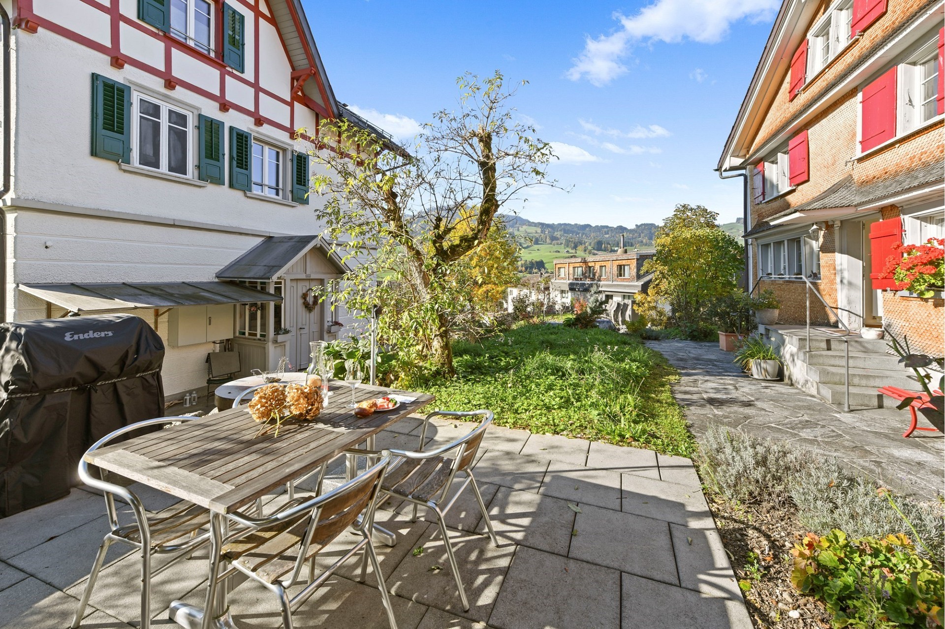 Garten-/Terrassenbereich zwischen zwei Wohnhäusern mit Blick ins Grüne