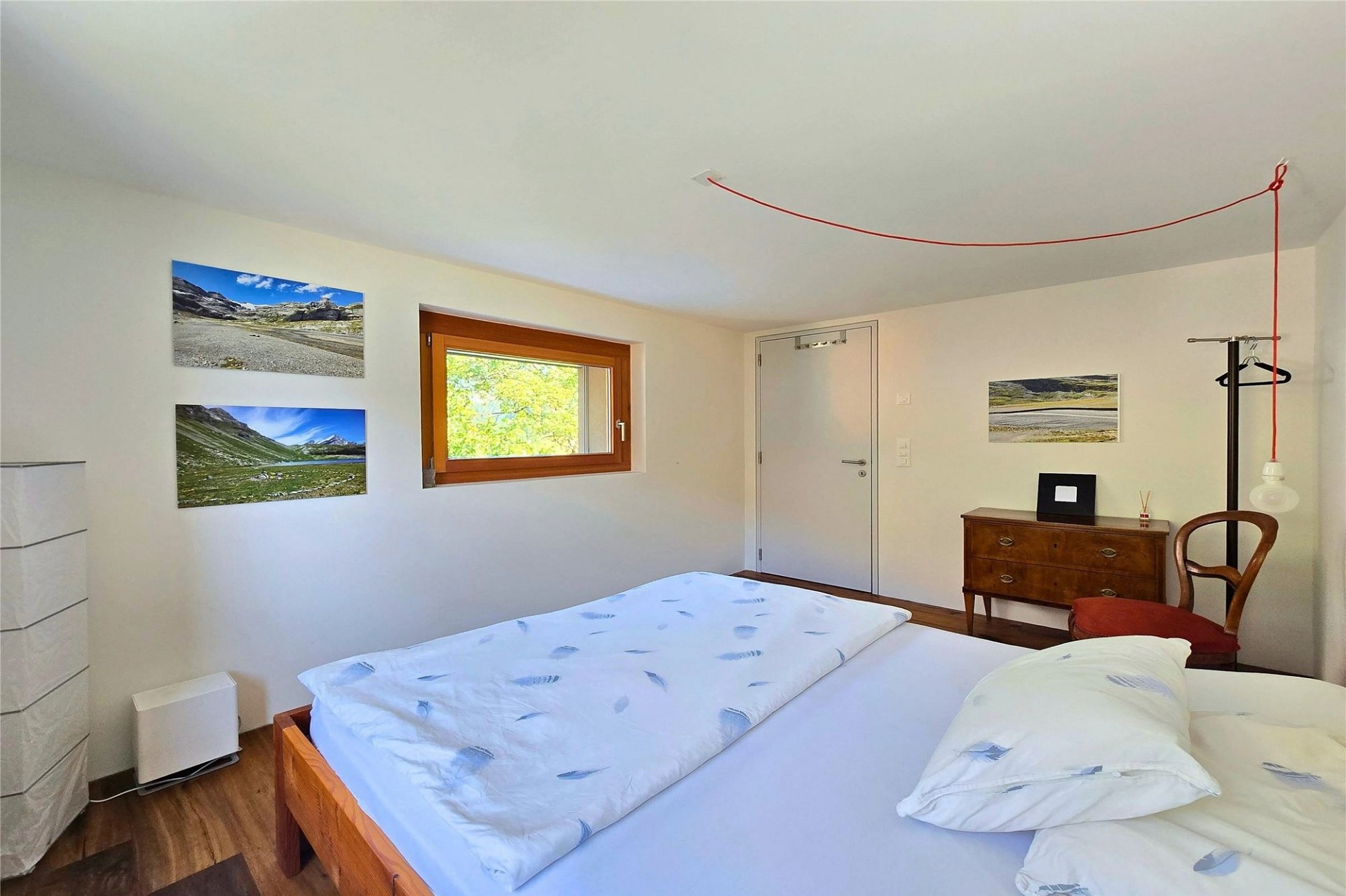 Helles Schlafzimmer mit Holzfenster und schlichter Möblierung