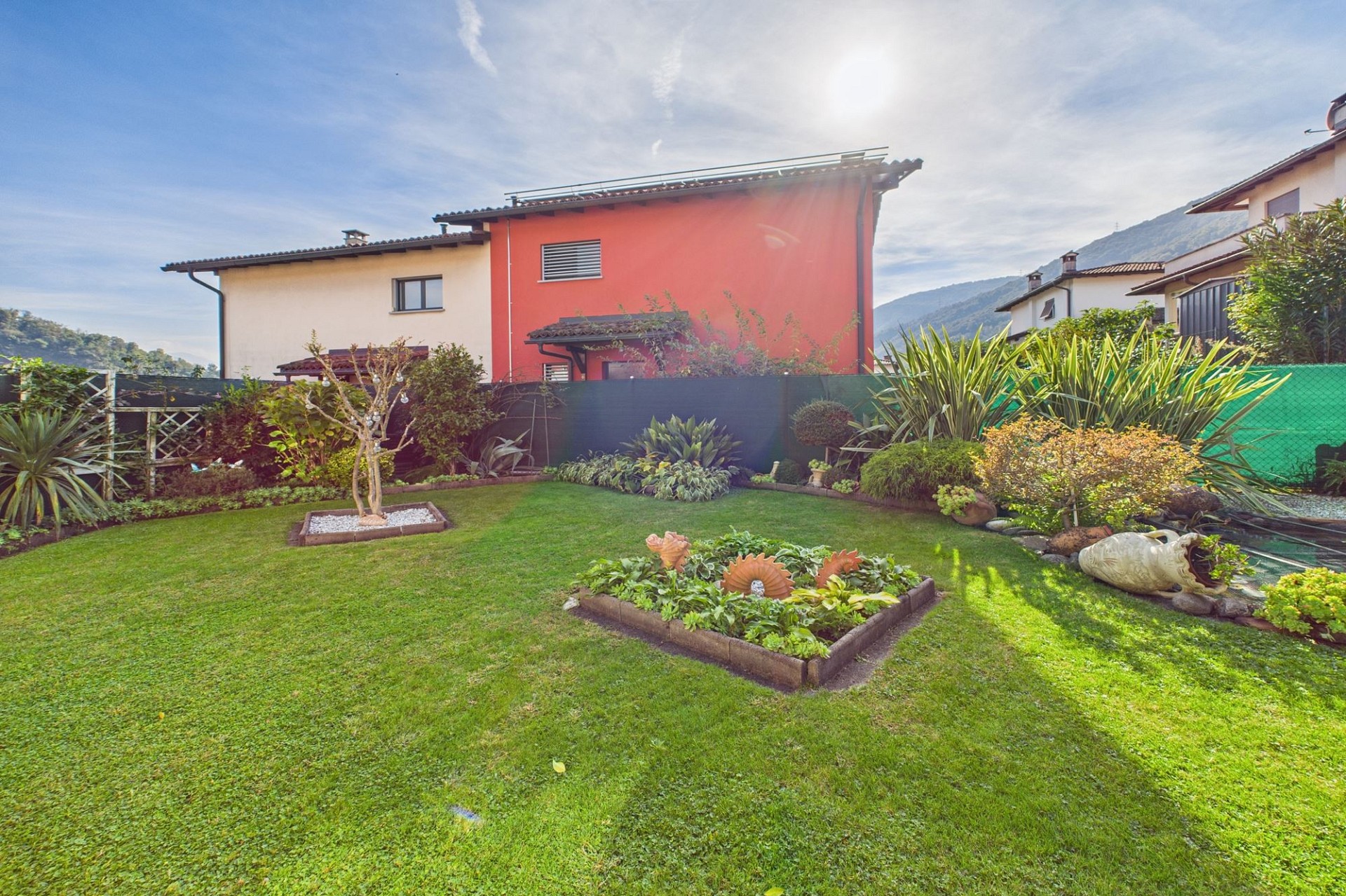 Gepflegter Garten mit Wohnhäusern und Bergkulisse