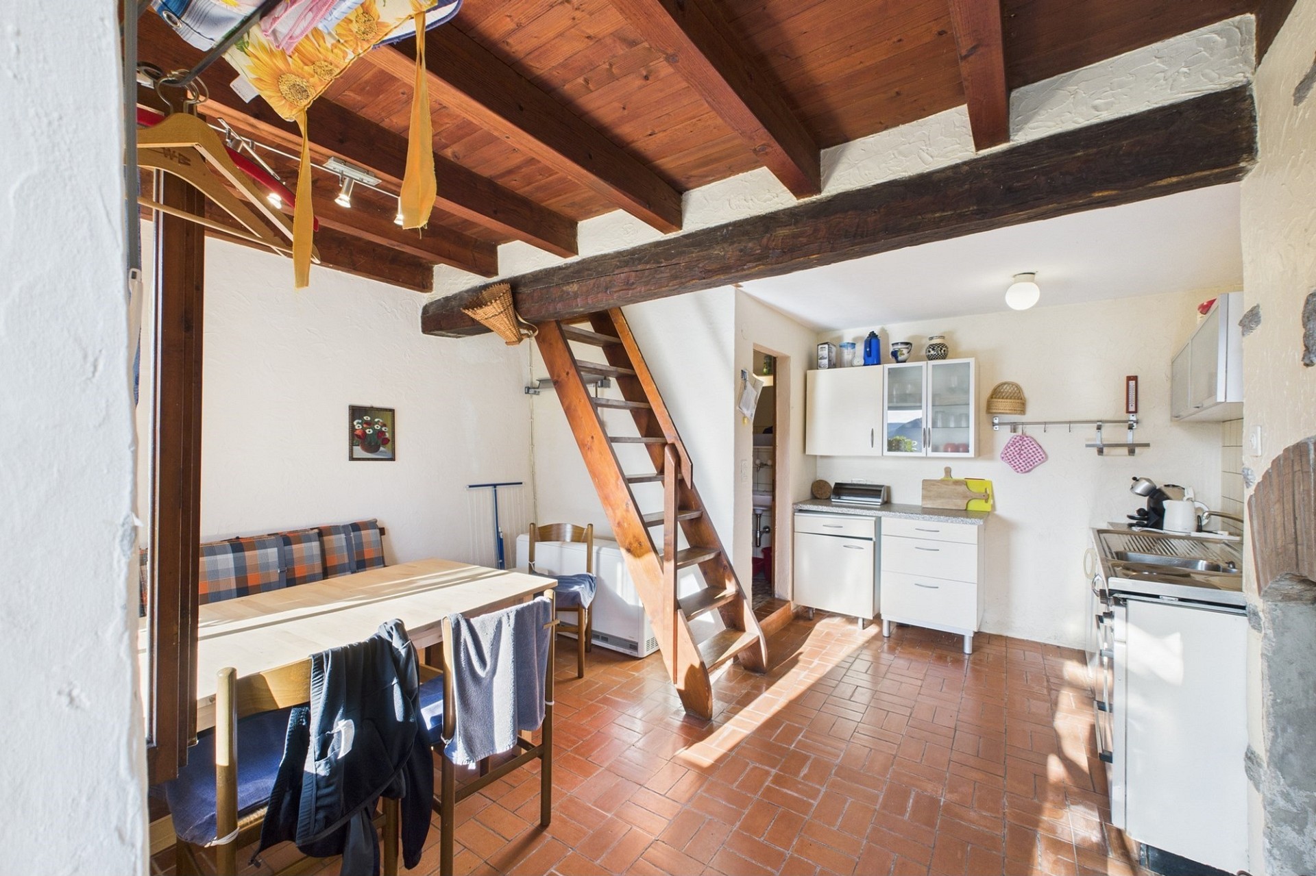 Gemütliche Wohnküche mit Holztreppe und sichtbaren Balken