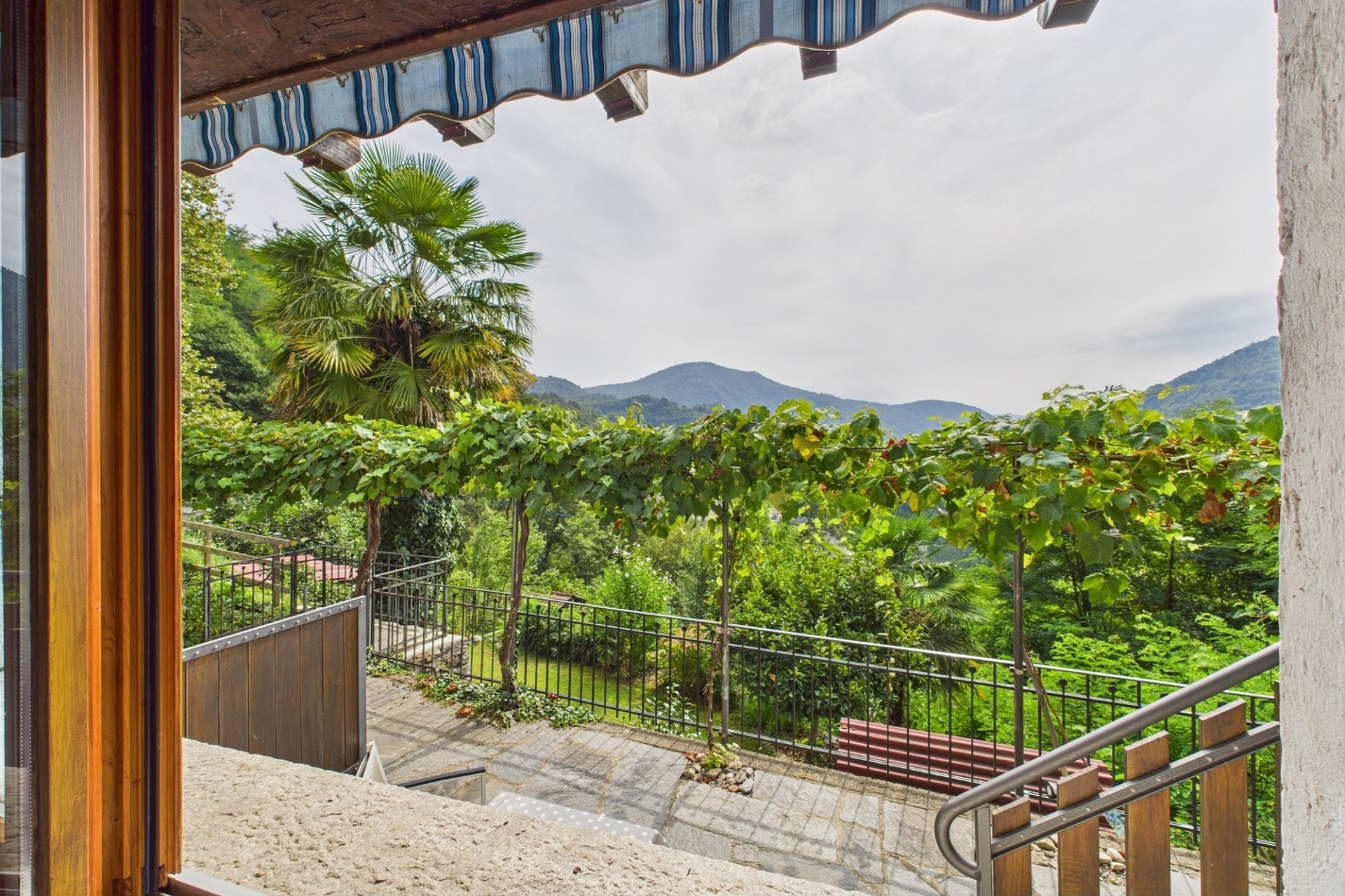 Blick von einer Terrasse auf grüne Berge und Garten