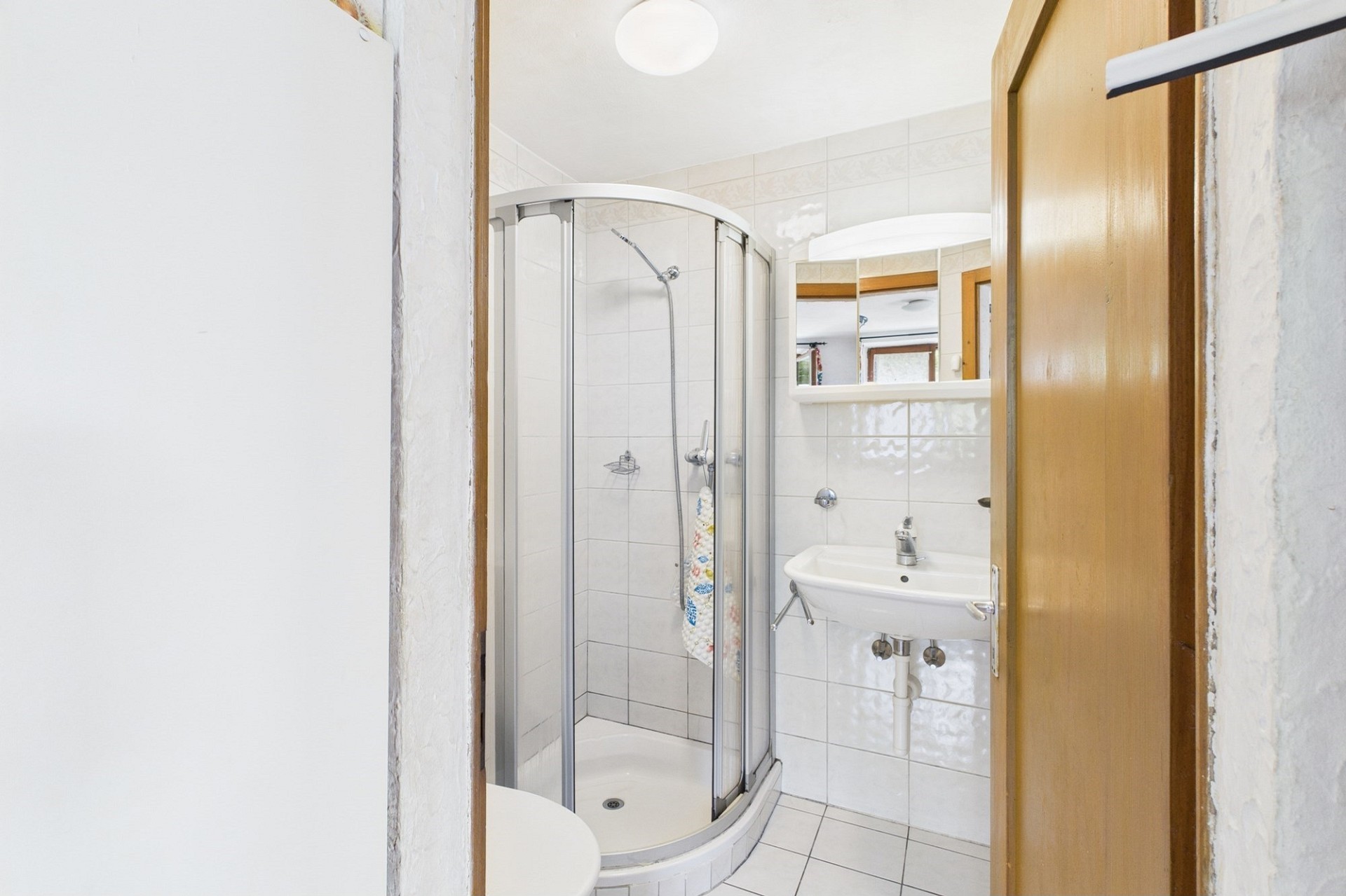 Kleines Badezimmer mit Duschkabine und Waschbecken