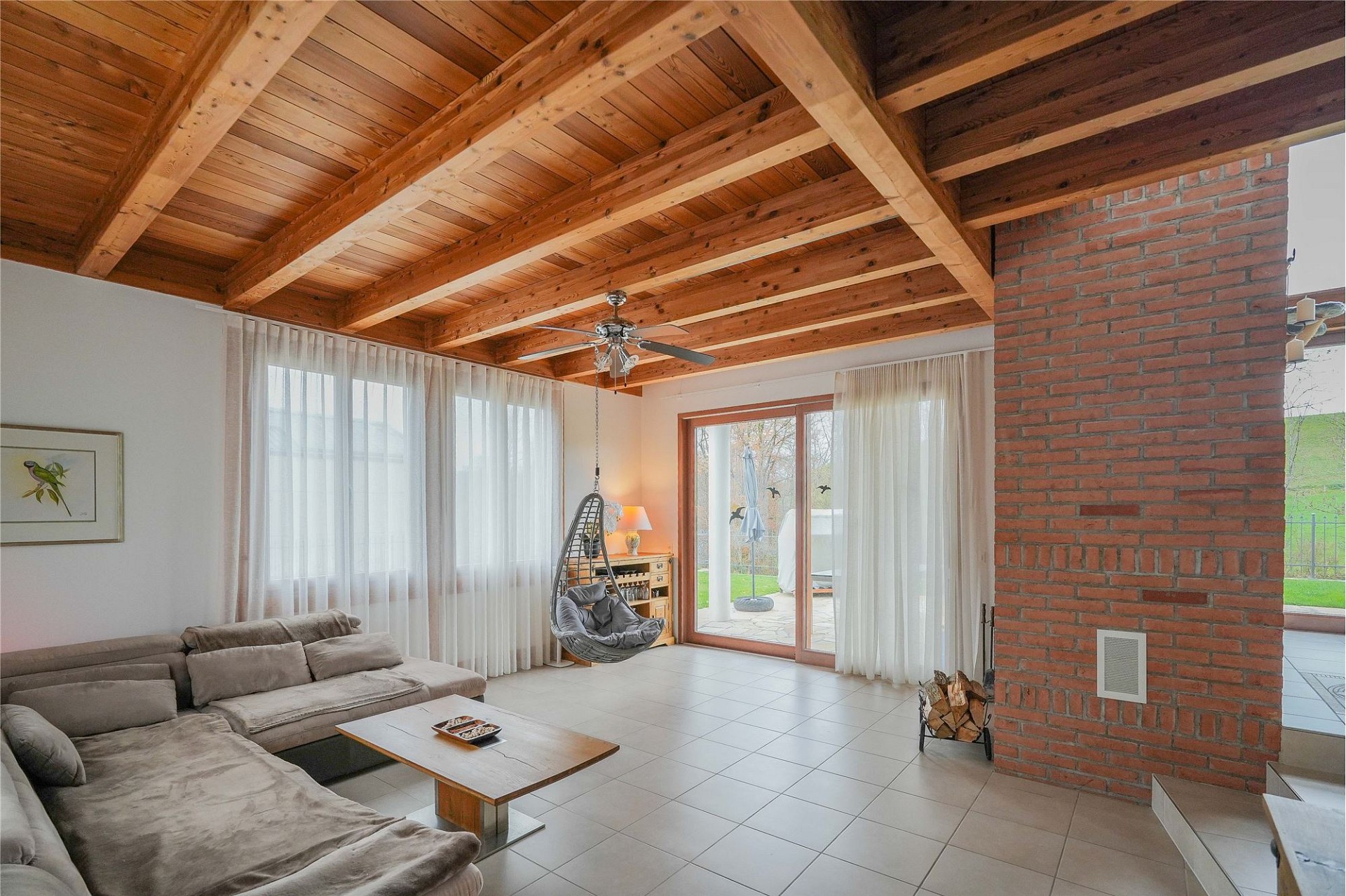 Heller Wohnraum mit sichtbaren Holzbalken und Kaminwand