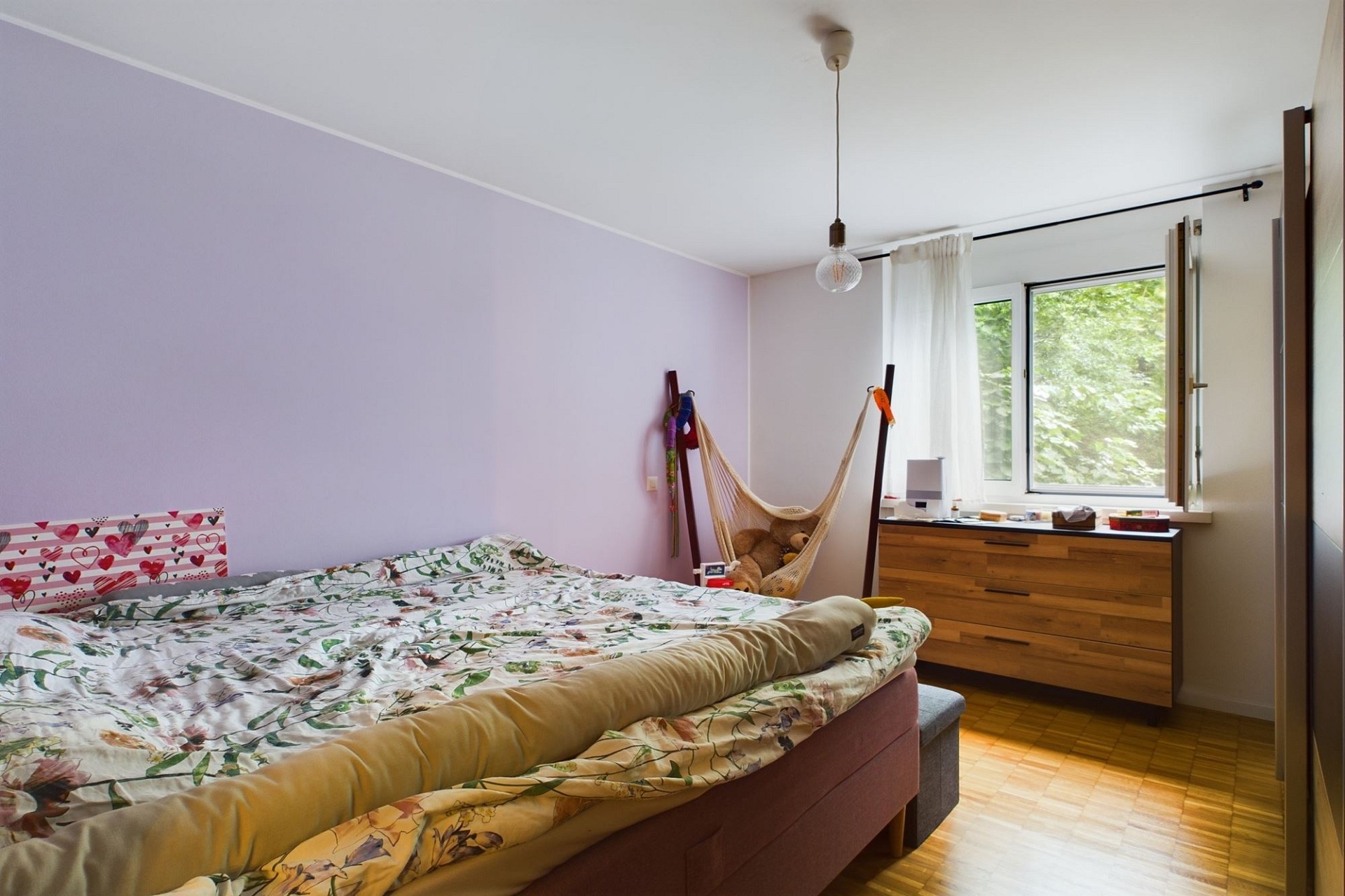 Helles Schlafzimmer mit Fenster und Holzkommode