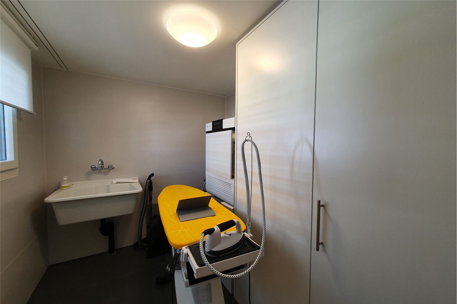 Hauswirtschafts-/Bügelraum mit Waschbecken und Bügelstation