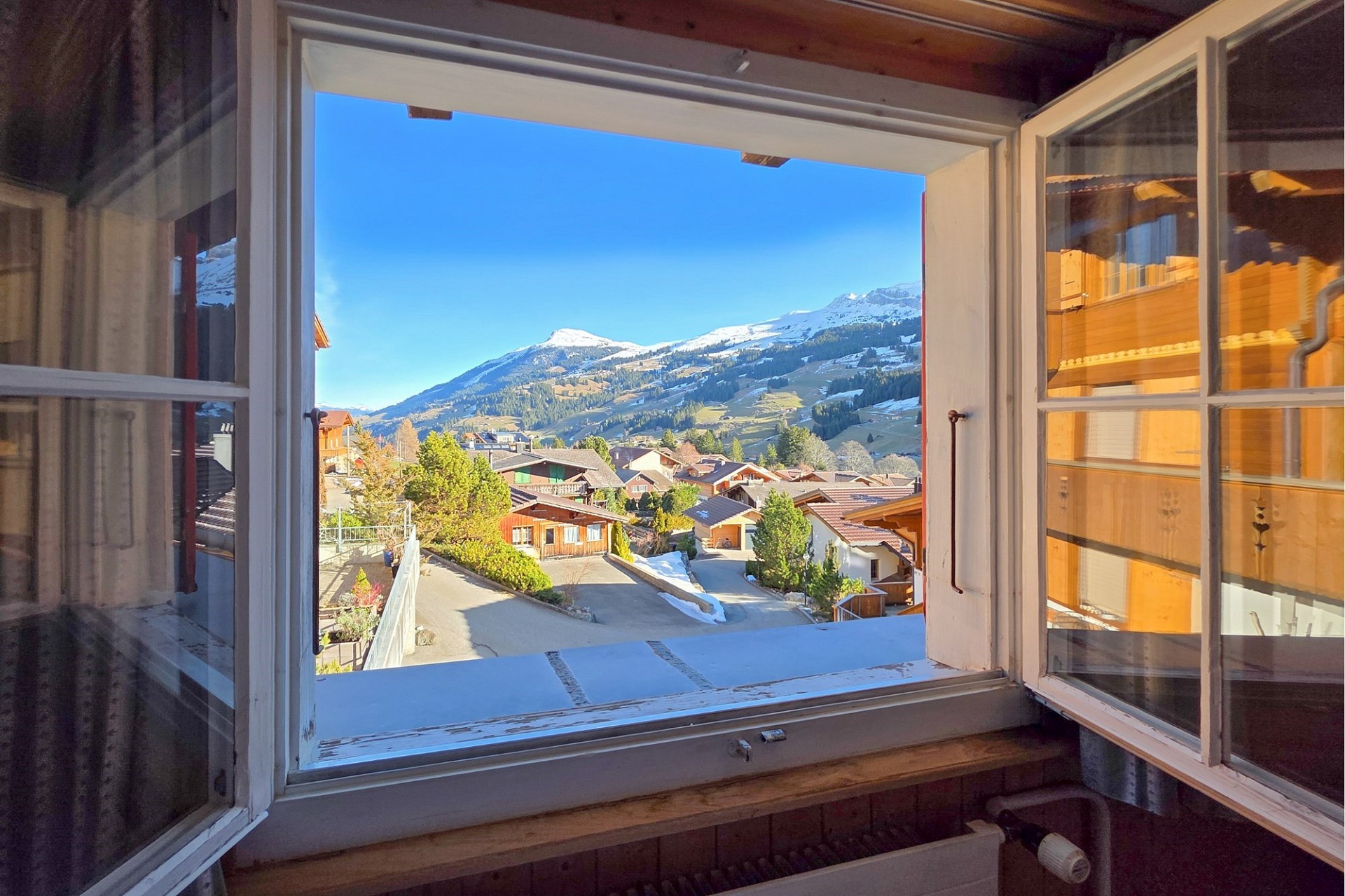 Blick aus einem geöffneten Fenster mit Bergpanorama