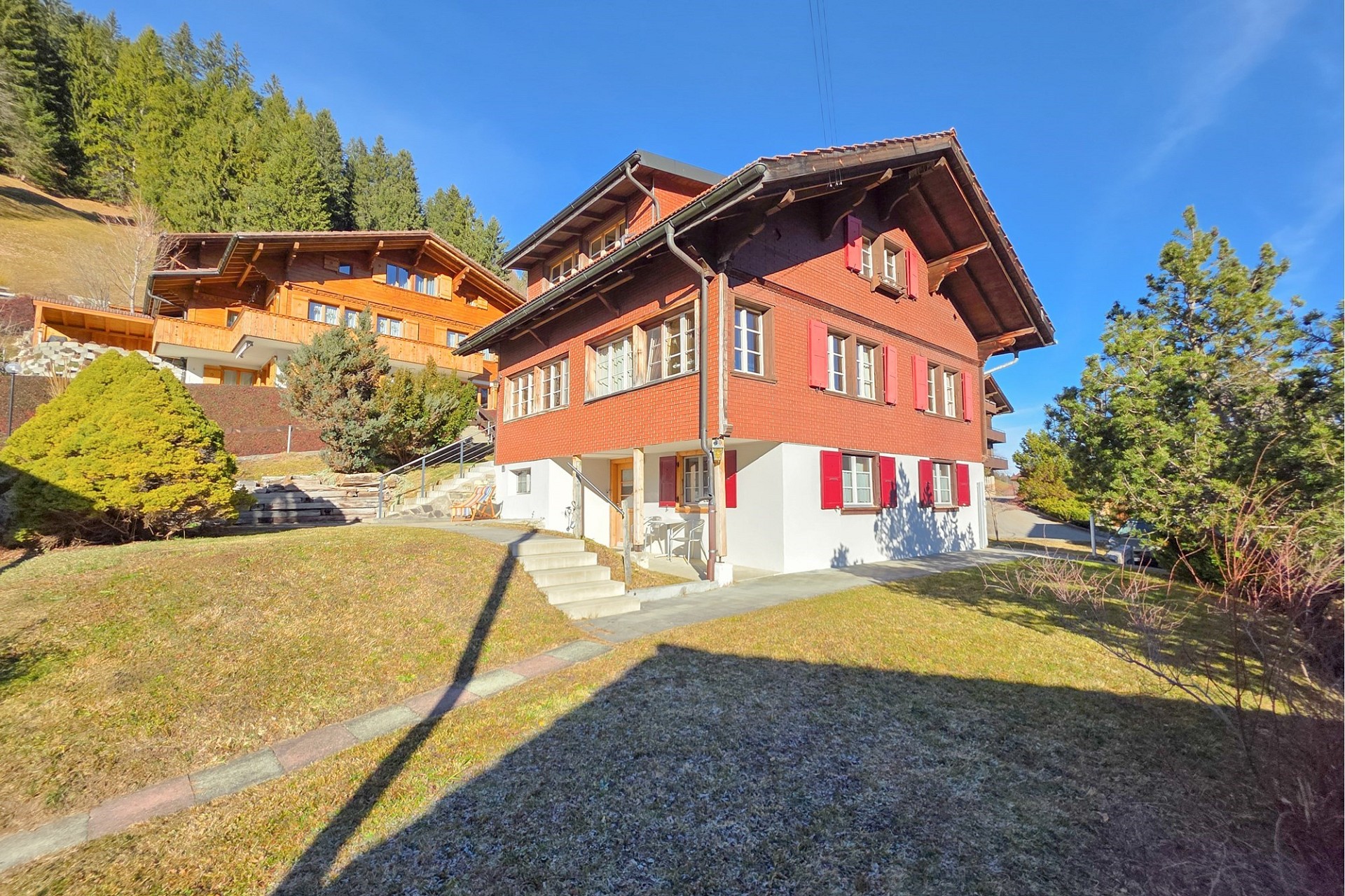 Alpines Wohnhaus mit Holzfassade und rotem Putz