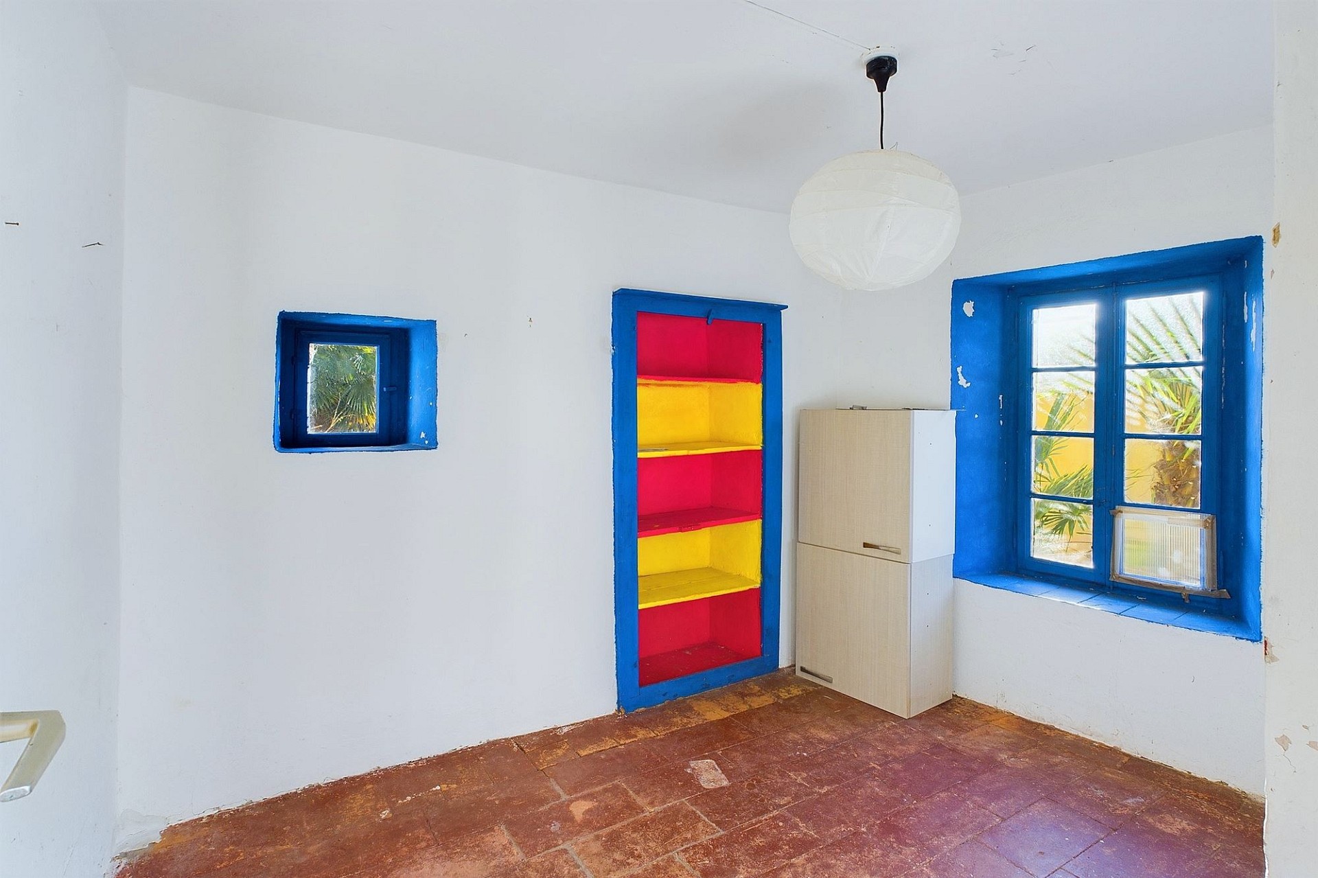 Kleiner Raum mit bunten Fenster- und Regalakzenten
