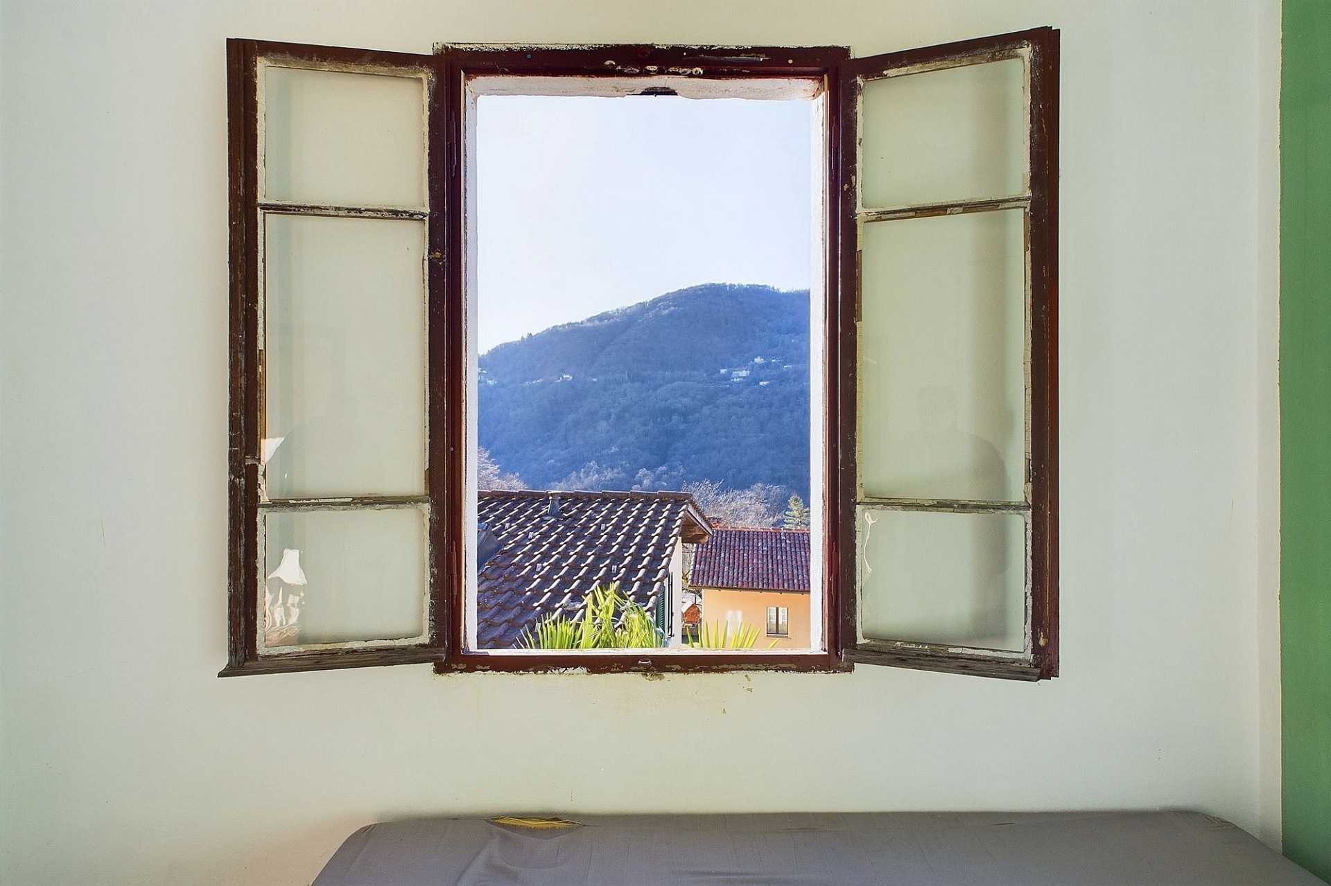 Zimmer mit offenem Holzfenster und Bergblick