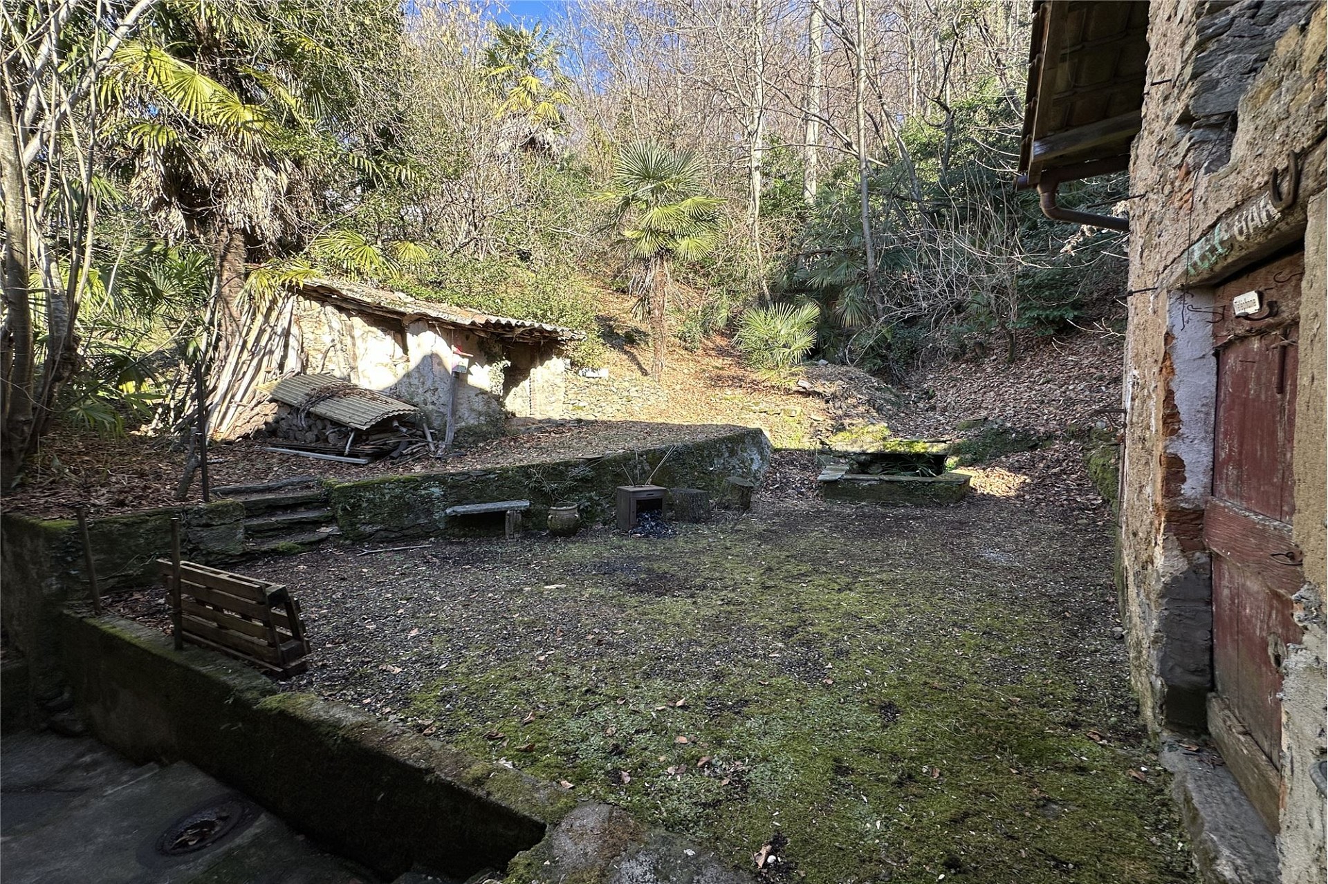 Verwilderter Außenhof mit Naturstein-Gebäuden