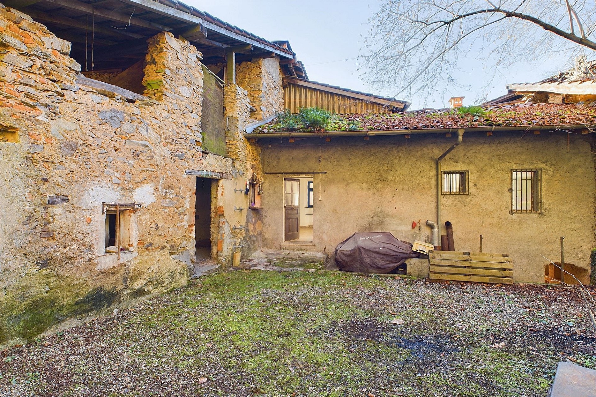 Rustikaler Innenhof mit alten Natursteinmauern und begrünten Dächern