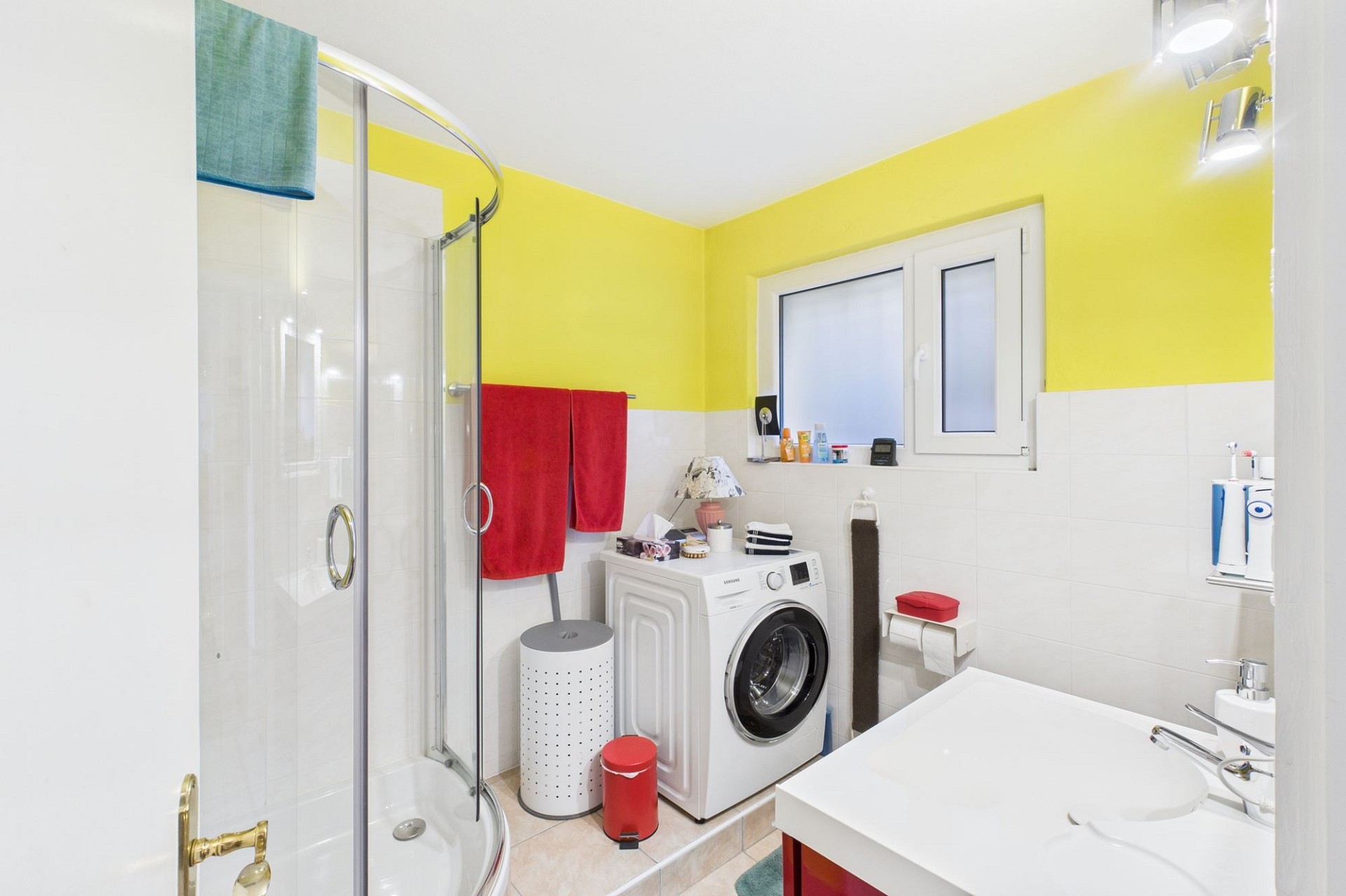 Helles, kompaktes Badezimmer mit Dusche und Waschmaschine