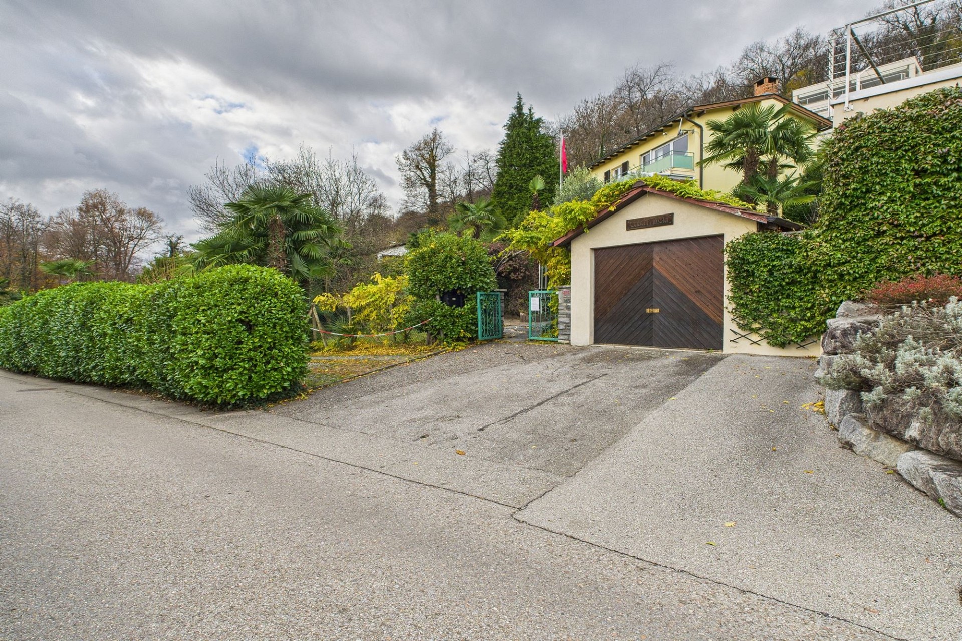 Einfahrt mit Garage und mediterranem Garten
