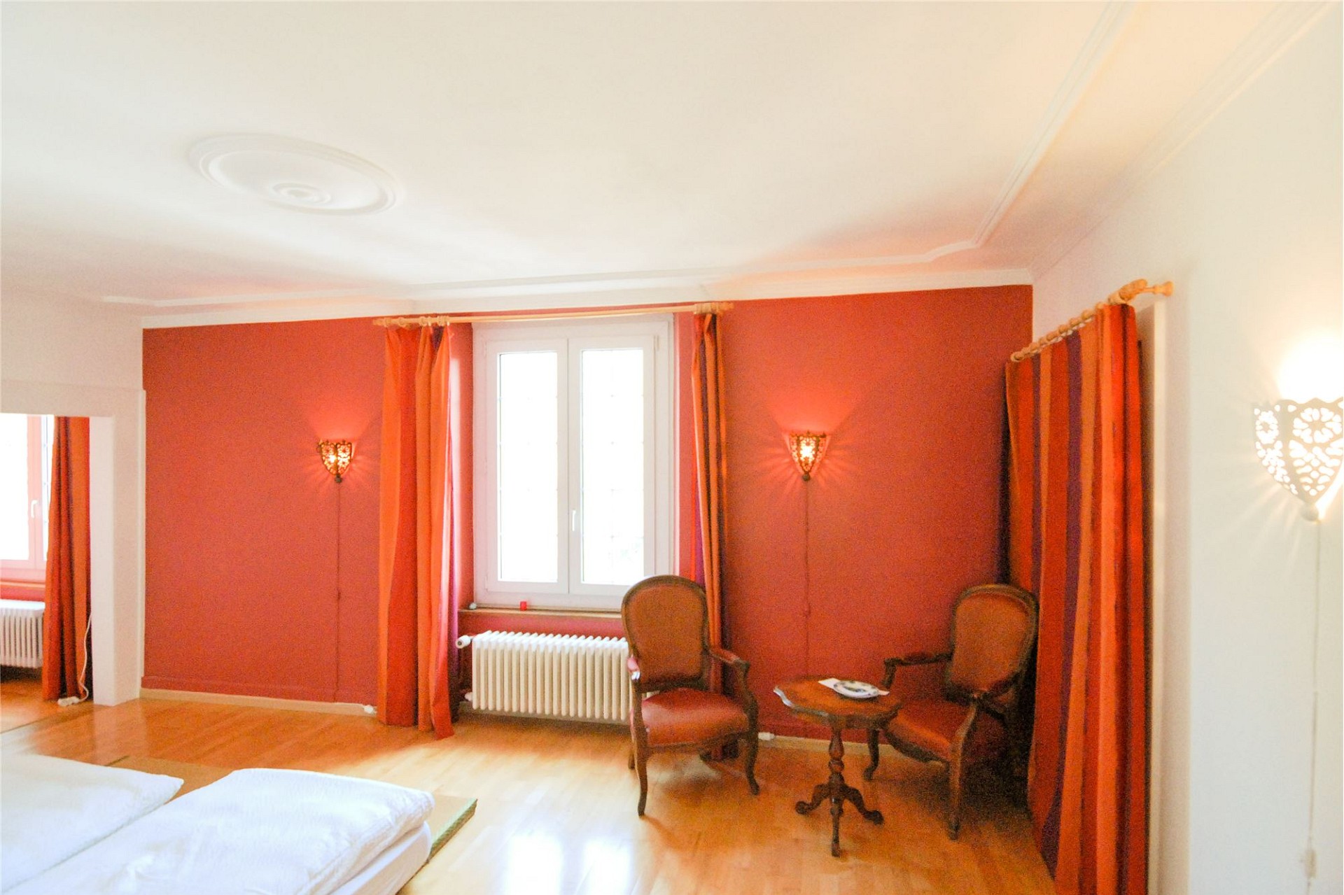 Elegant eingerichtetes Schlafzimmer mit warmen Rot- und Orangetönen