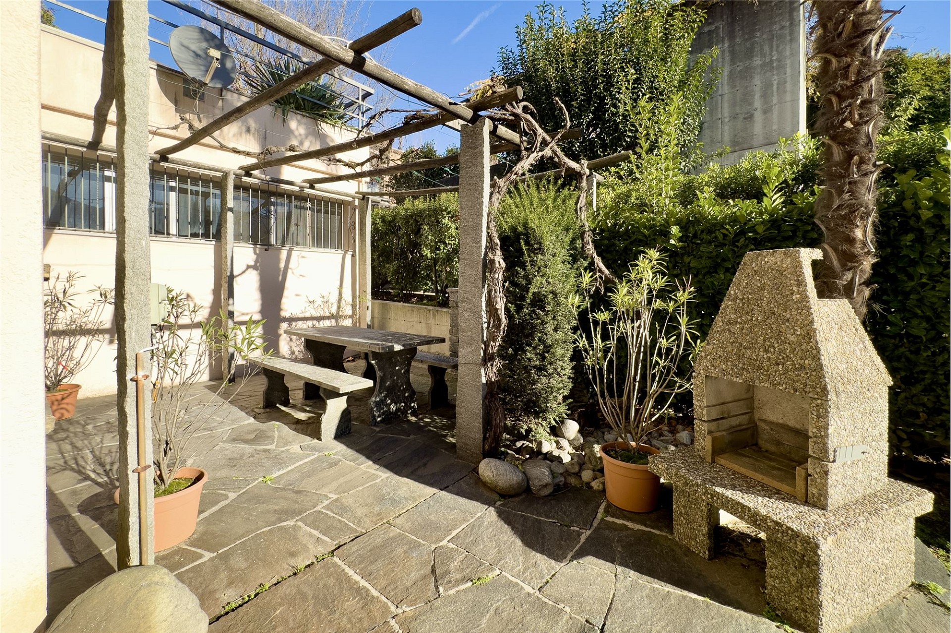 Gepflasterte Garten-Terrasse mit Grill und Pergola