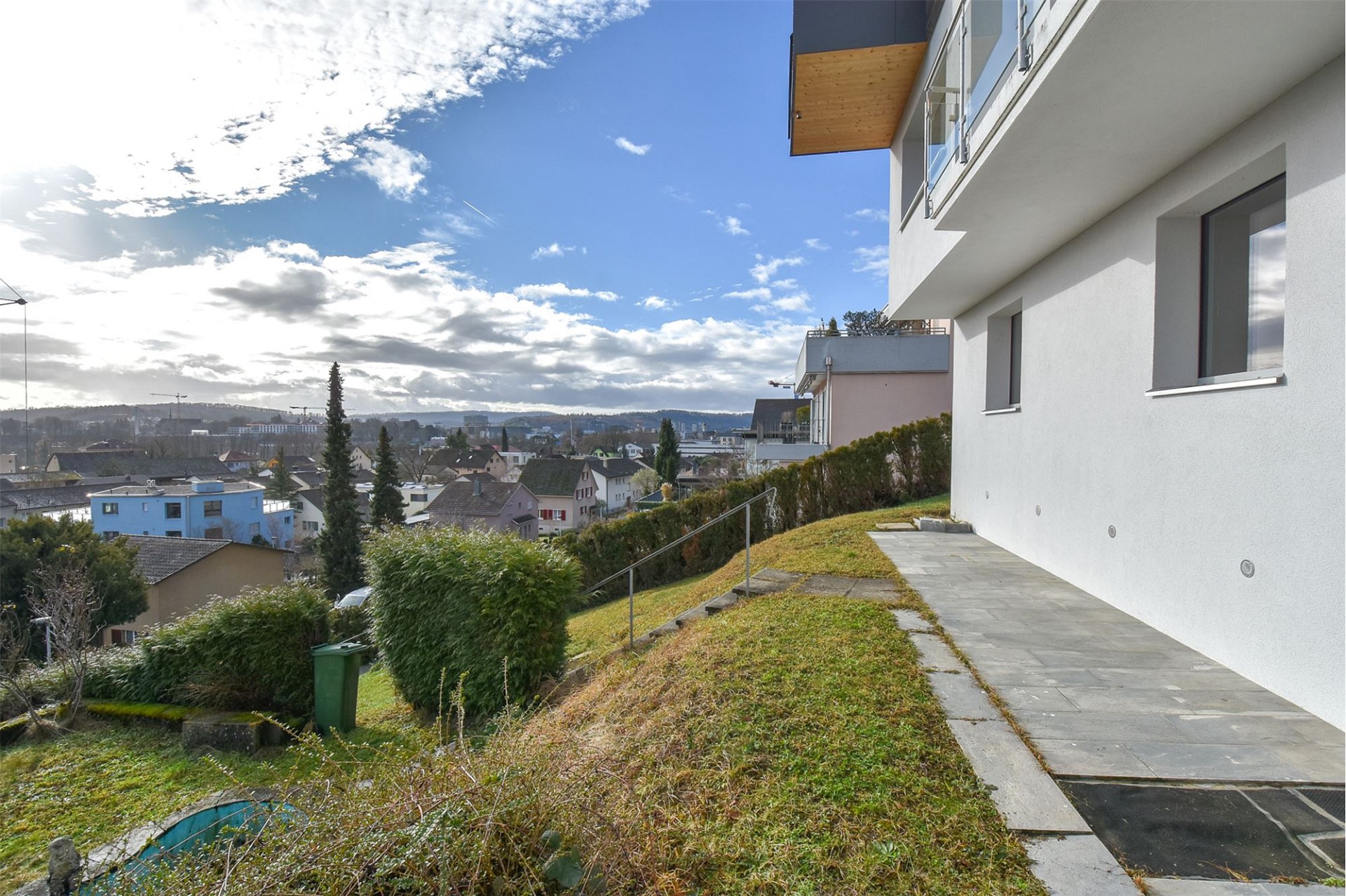 Außenansicht eines modernen Hauses mit Hanglage und Stadtblick