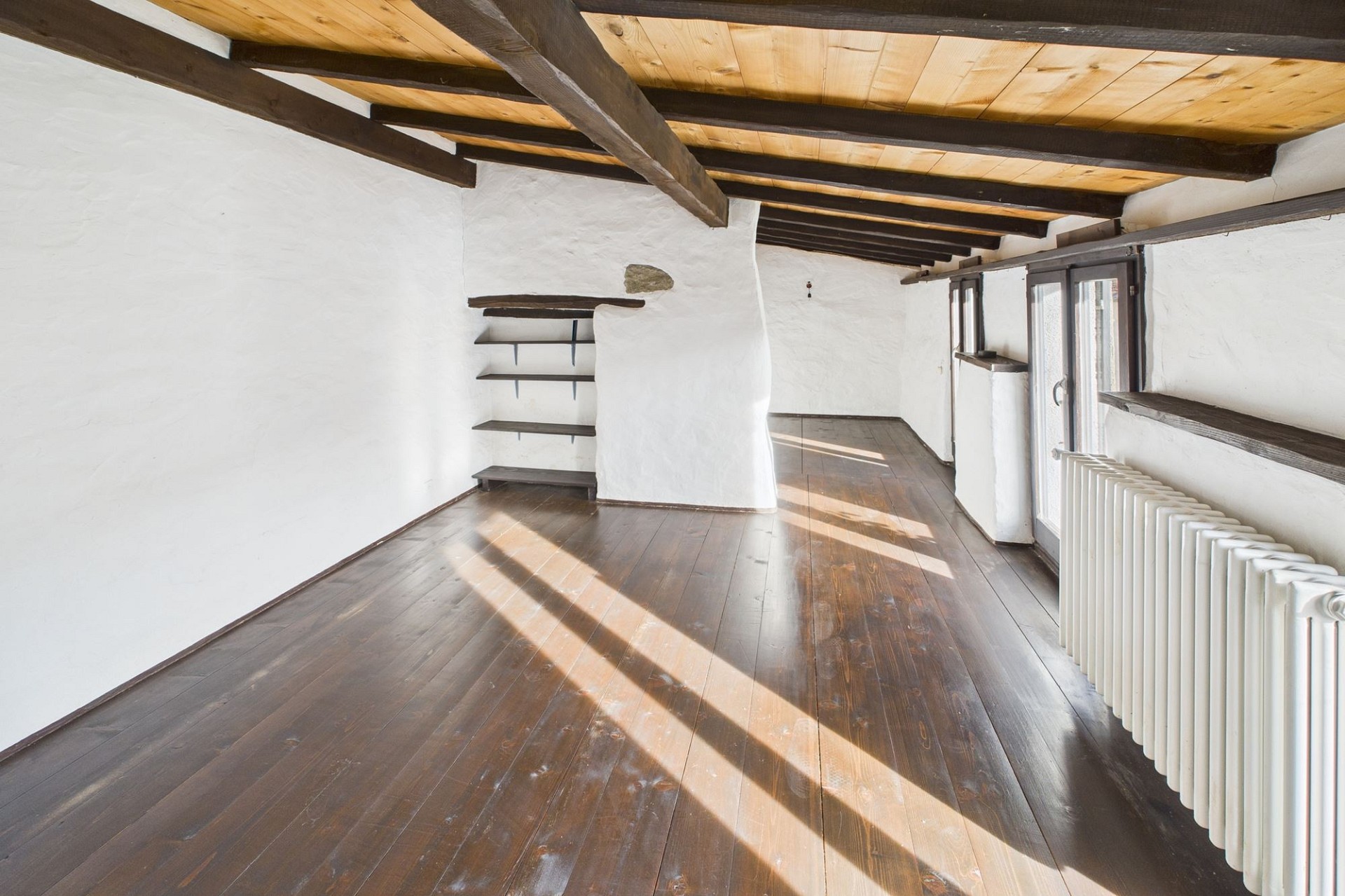 Heller Raum mit sichtbaren Holzbalken und dunklem Dielenboden