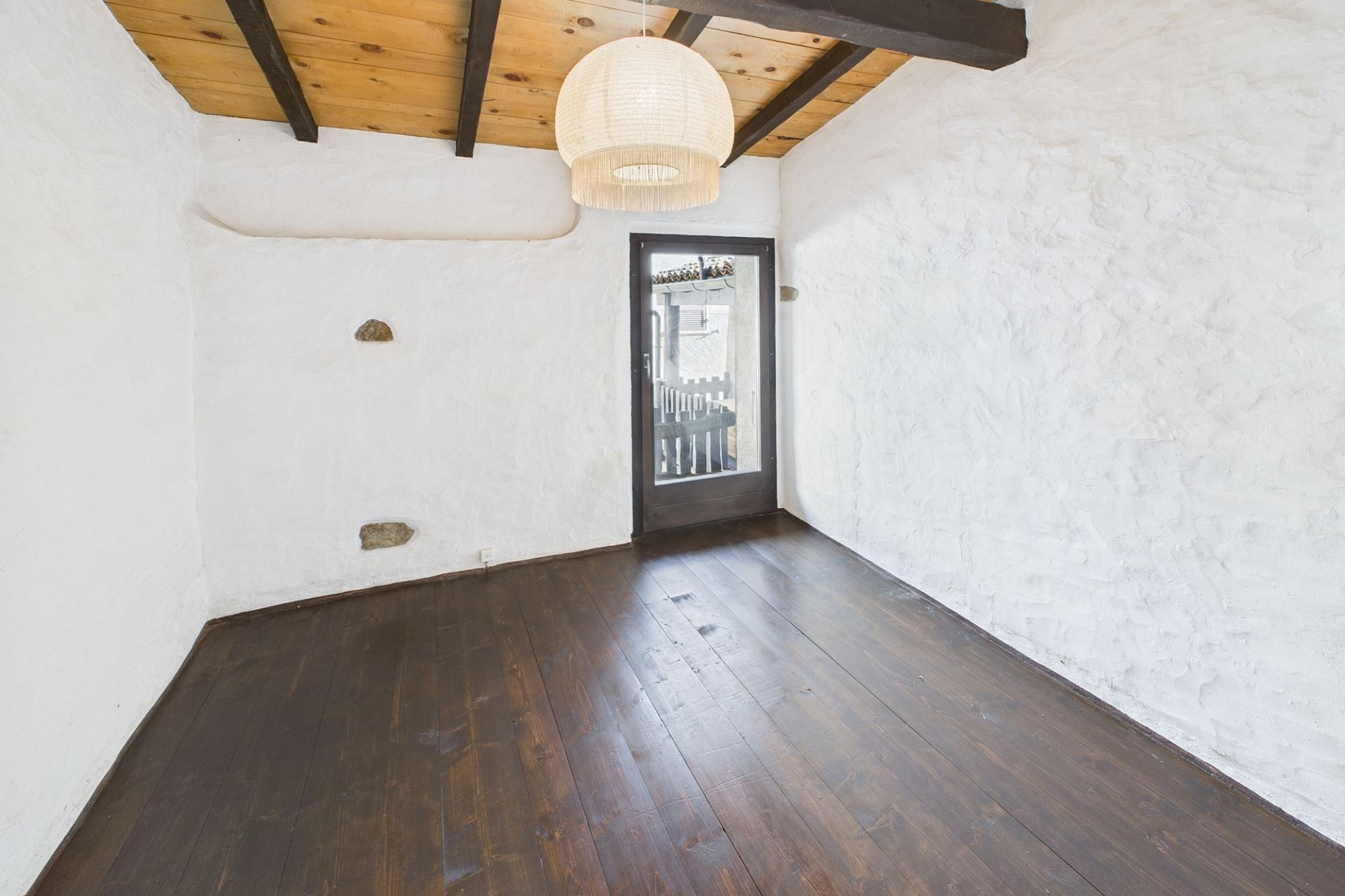 Kleiner rustikaler Raum mit dunklem Holzboden