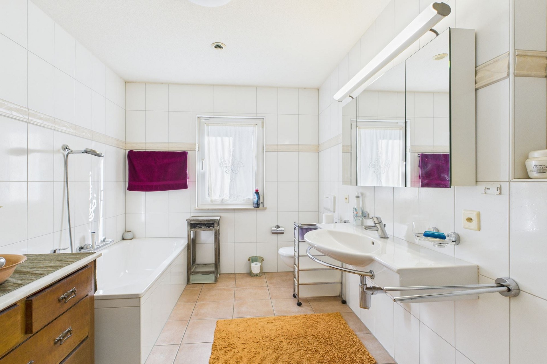 Helles, schlichtes Badezimmer mit Badewanne, Waschtisch und Spiegel