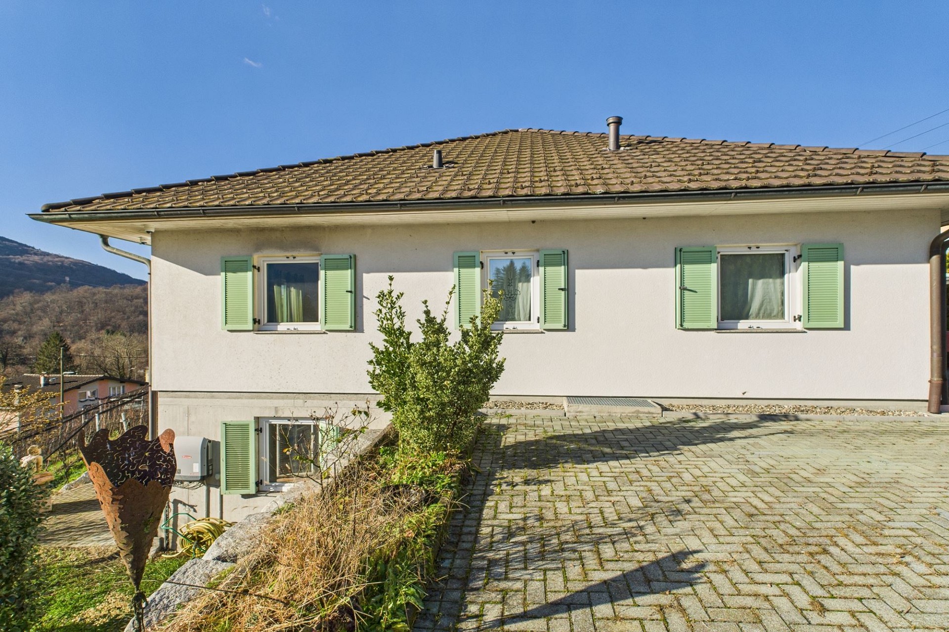 Hausansicht mit Satteldach und grünen Fensterläden