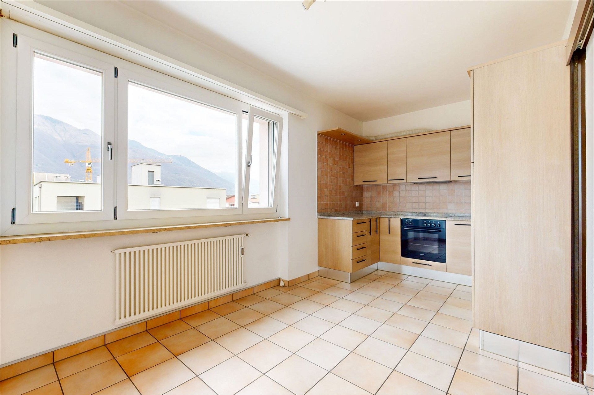 Helle Küche mit großem Fenster und Fliesenboden