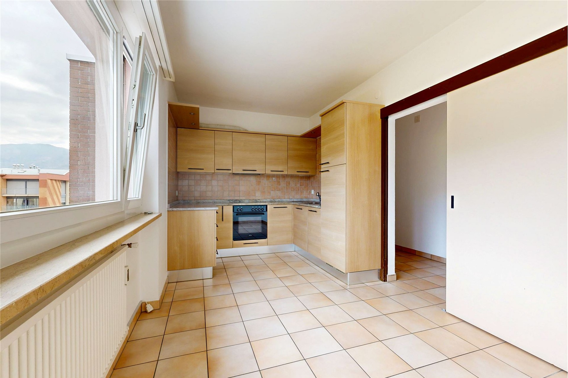 Helle Küche mit großem Fenster und Fliesenboden