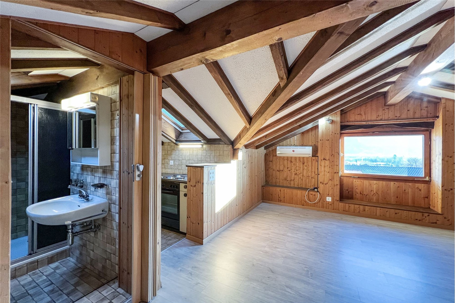 Dachgeschossraum mit Holzverkleidung und Badbereich