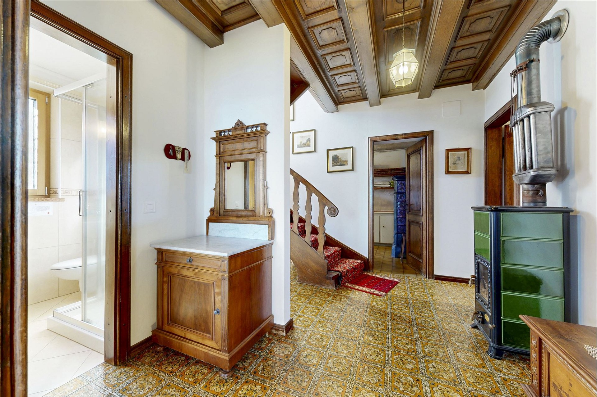 Historischer Flur mit Holzofen und Treppe