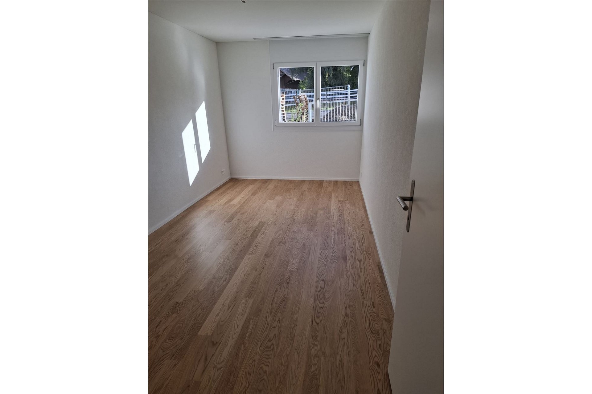 Heller leerer Raum mit Parkettboden und Fenster