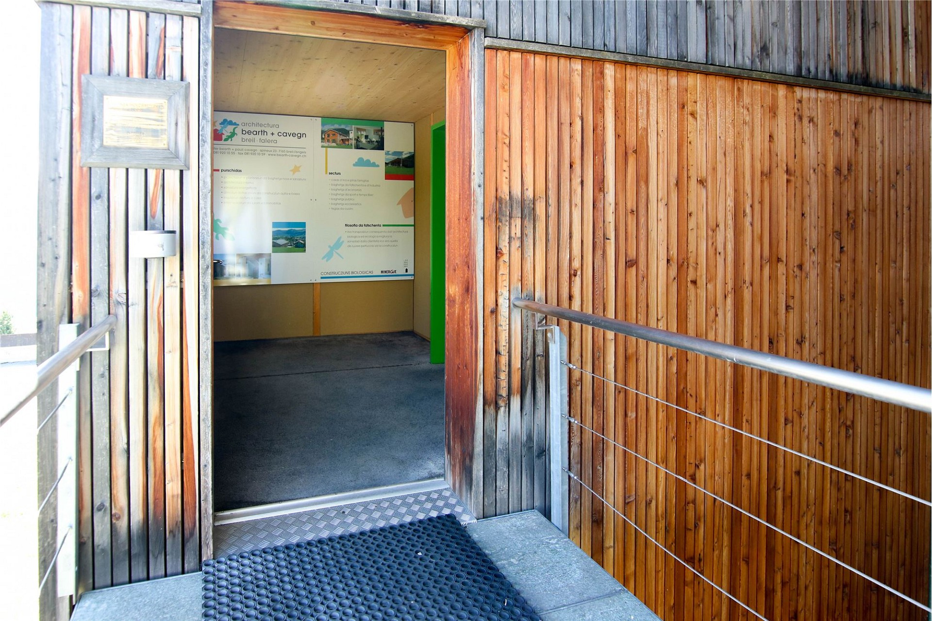 Außeneingang mit Holzverkleidung und Hinweis auf Büro-/Ausstellungsbereich