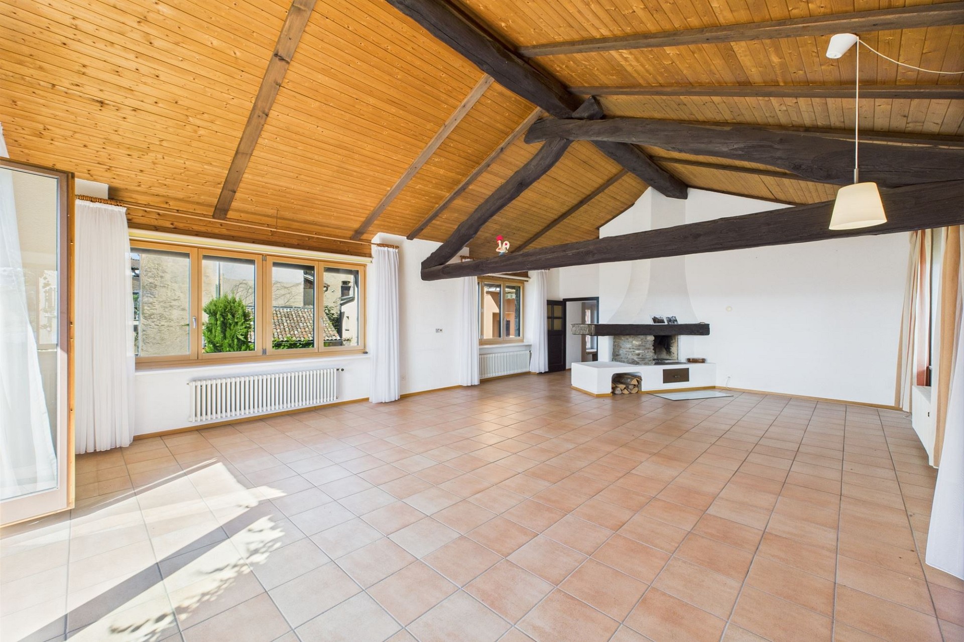 Großer Wohnraum mit sichtbaren Holzbalken und Kamin