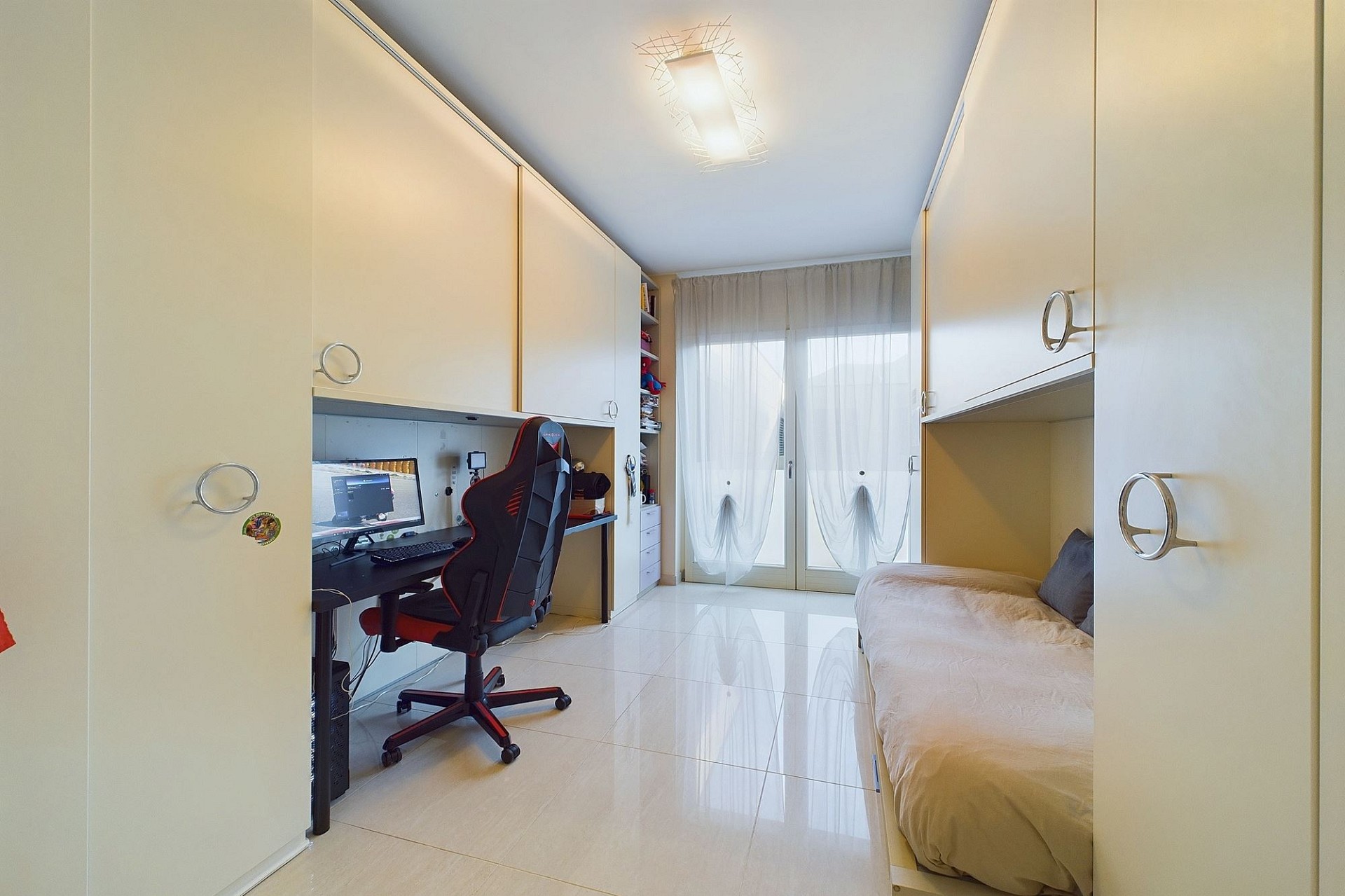 Schmales Kinderzimmer mit Arbeitsbereich und Bett