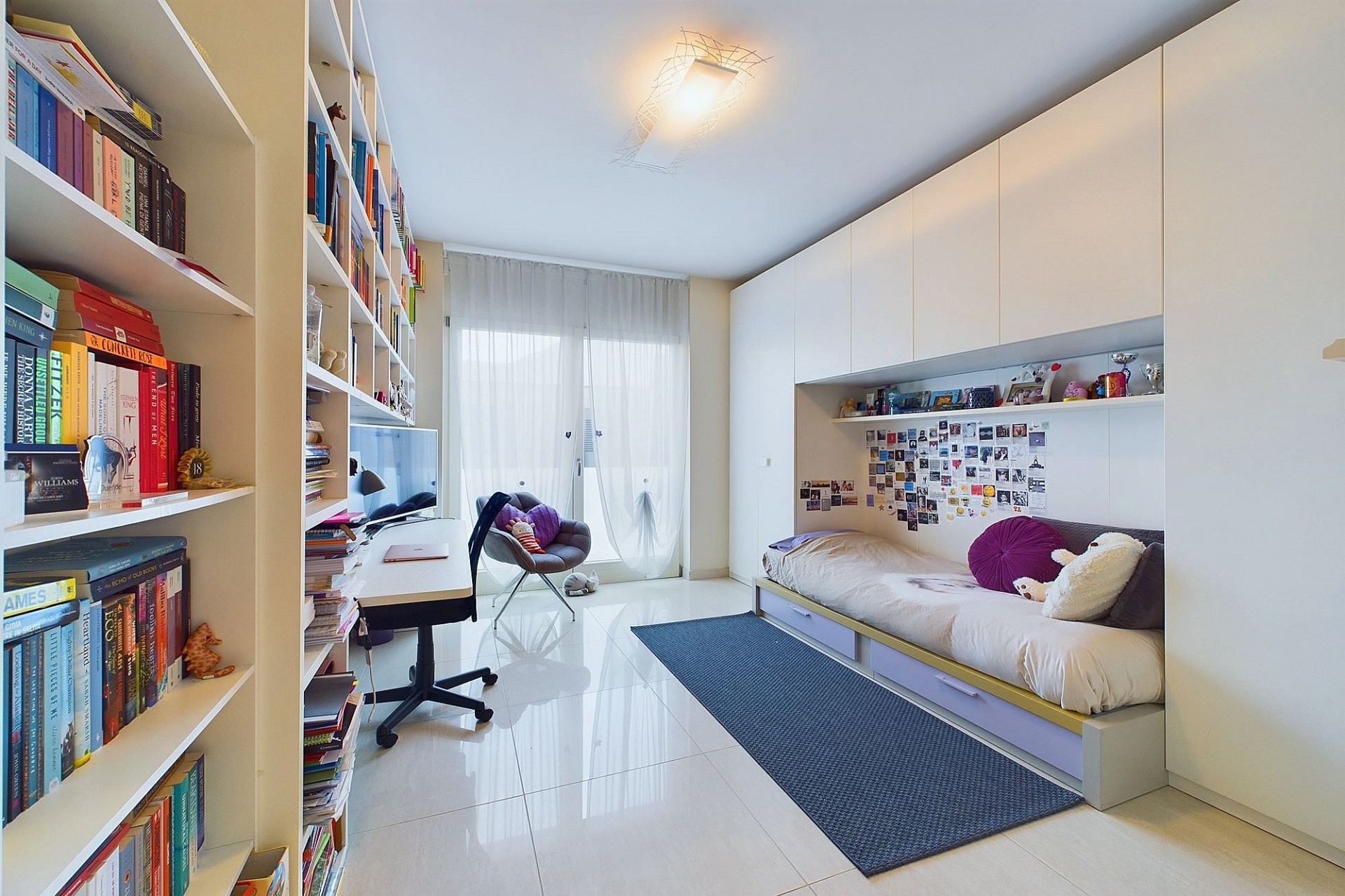 Helles Jugendzimmer mit Bett und Bücherregalen