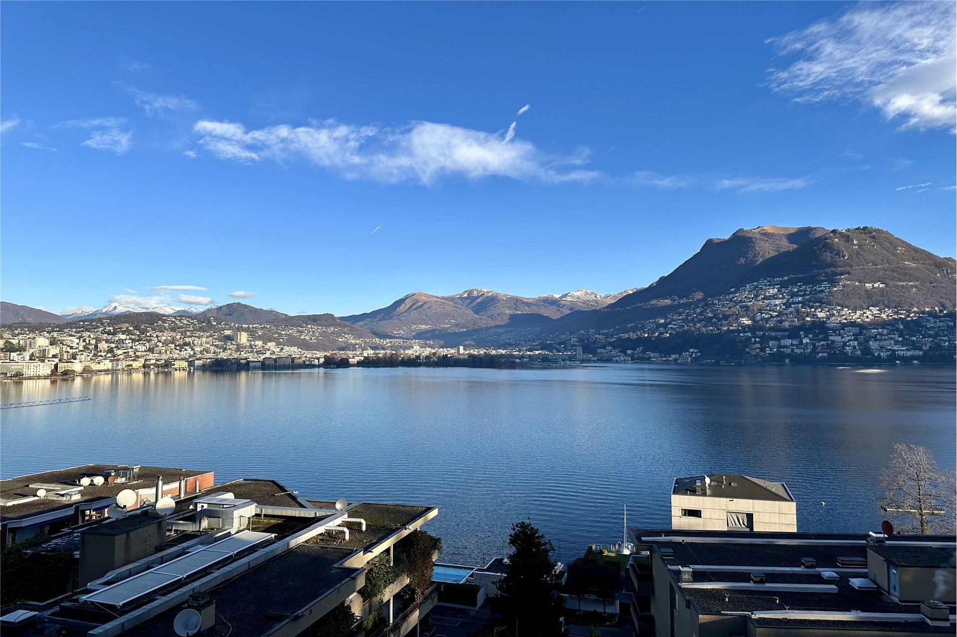 Seeblick mit Bergen und Stadt am Ufer