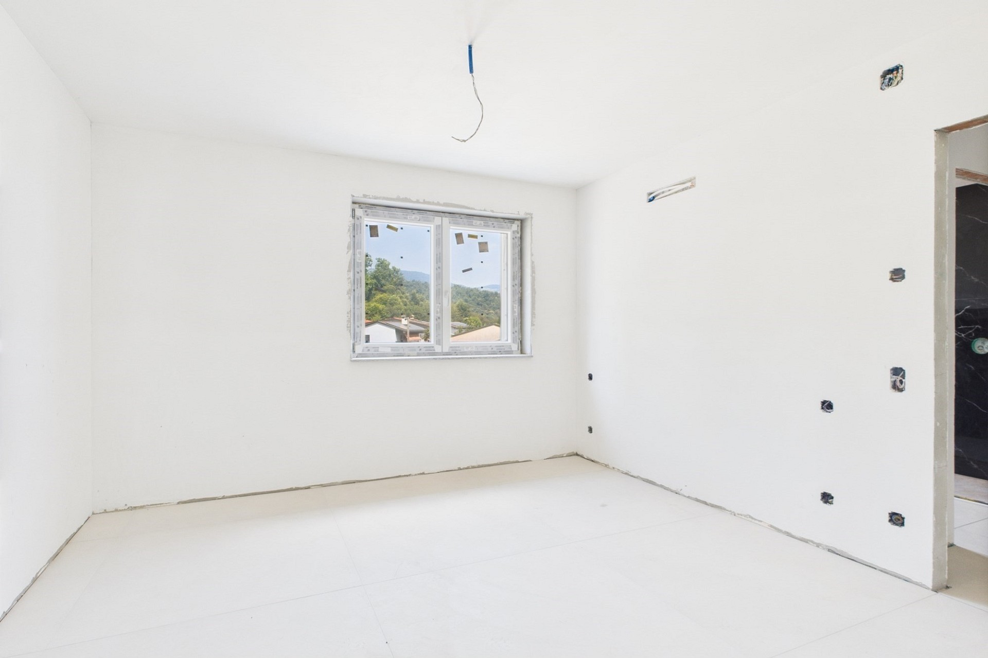 Unfertiger leerer Innenraum mit Fenster und Rohinstallationen