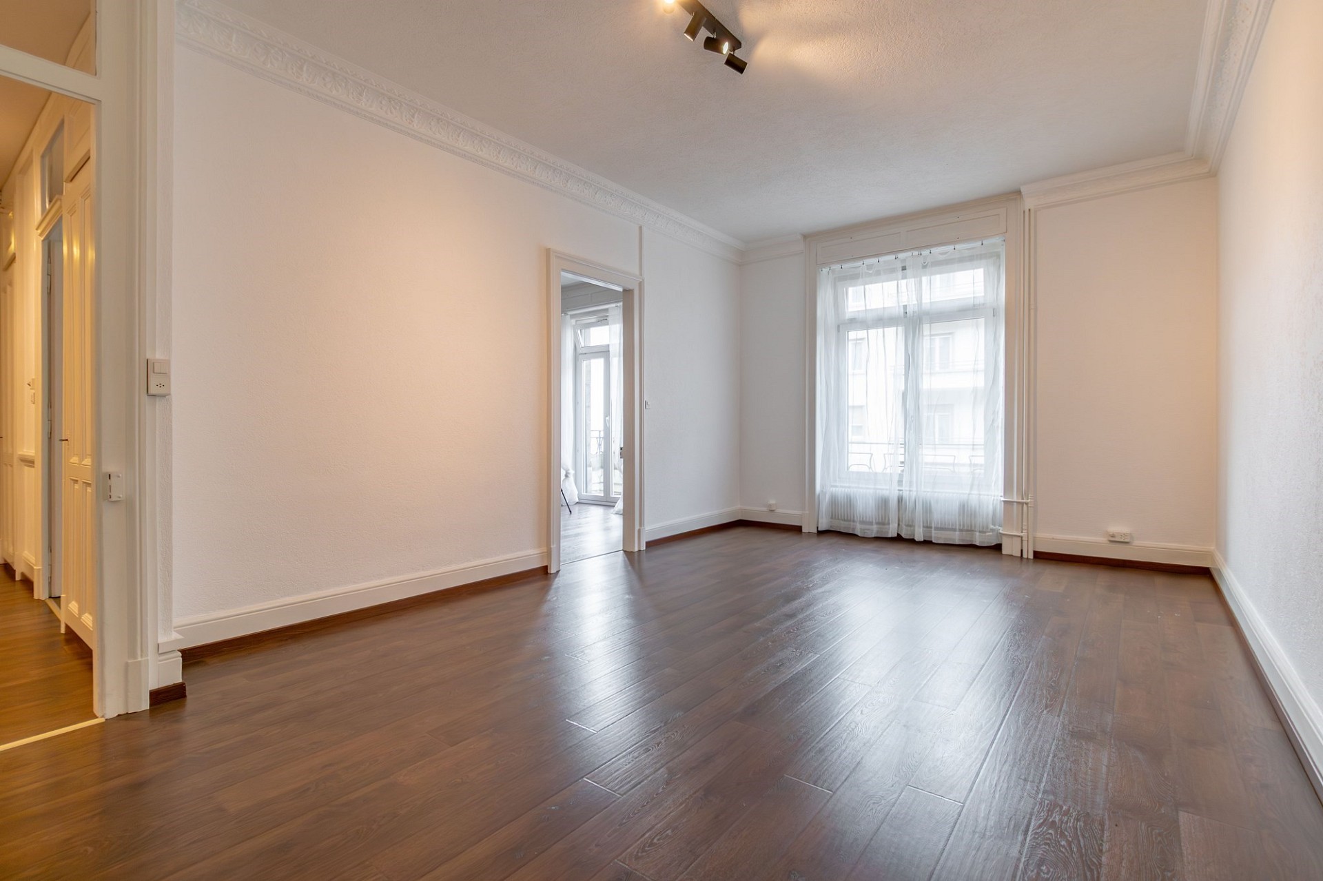Leerer Altbau-Wohnraum mit Fischgrätoptik-Fenster und Stuck