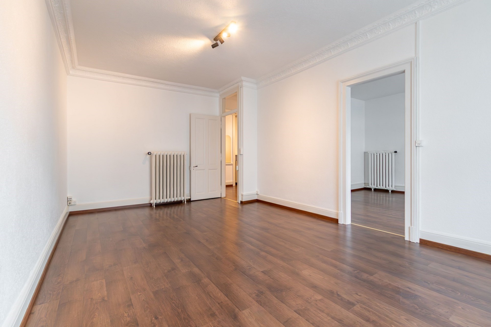Heller leerer Wohnraum mit Parkett und Stuck
