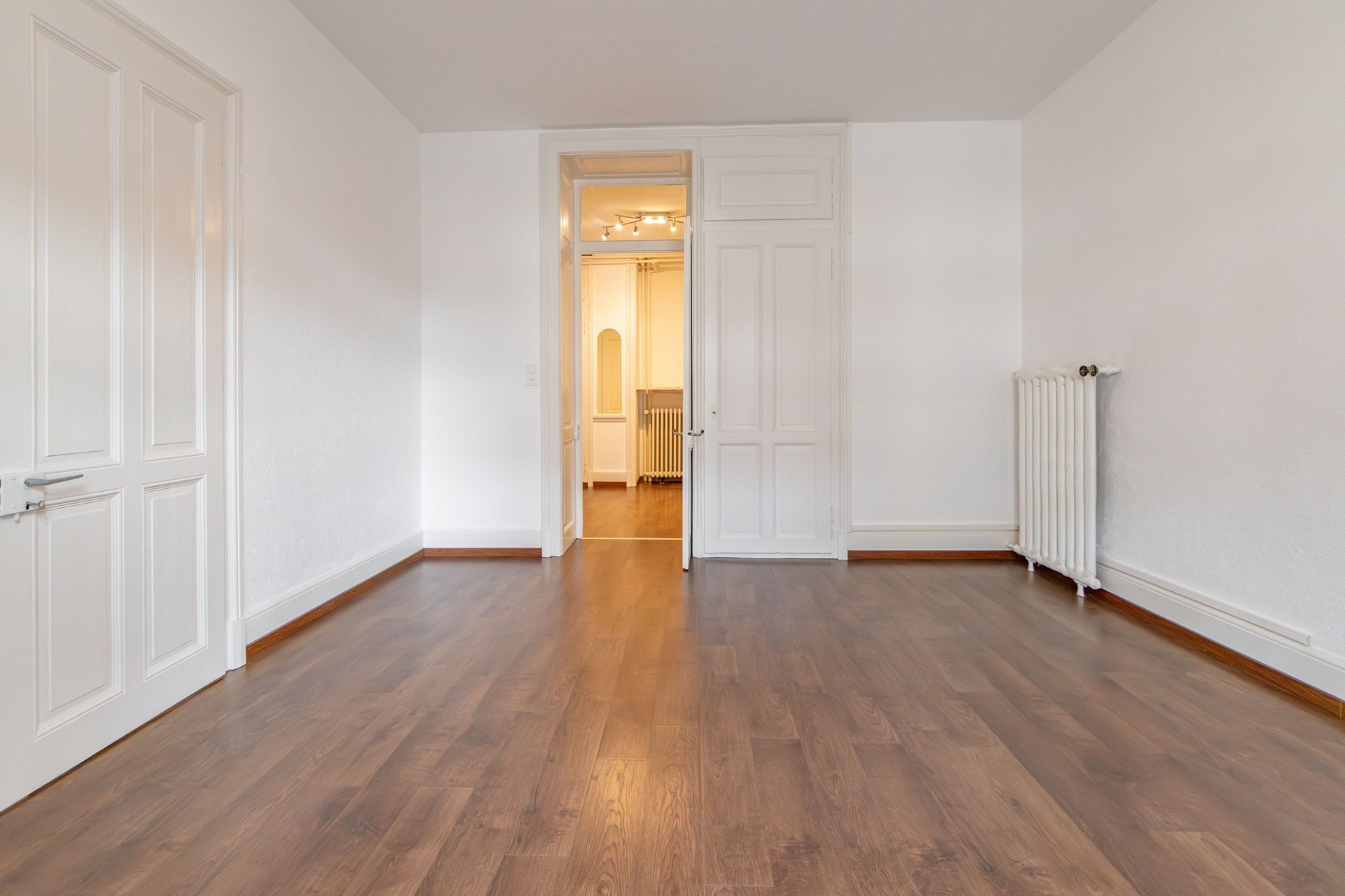 Heller leerer Raum mit Holzboden und weißen Türen