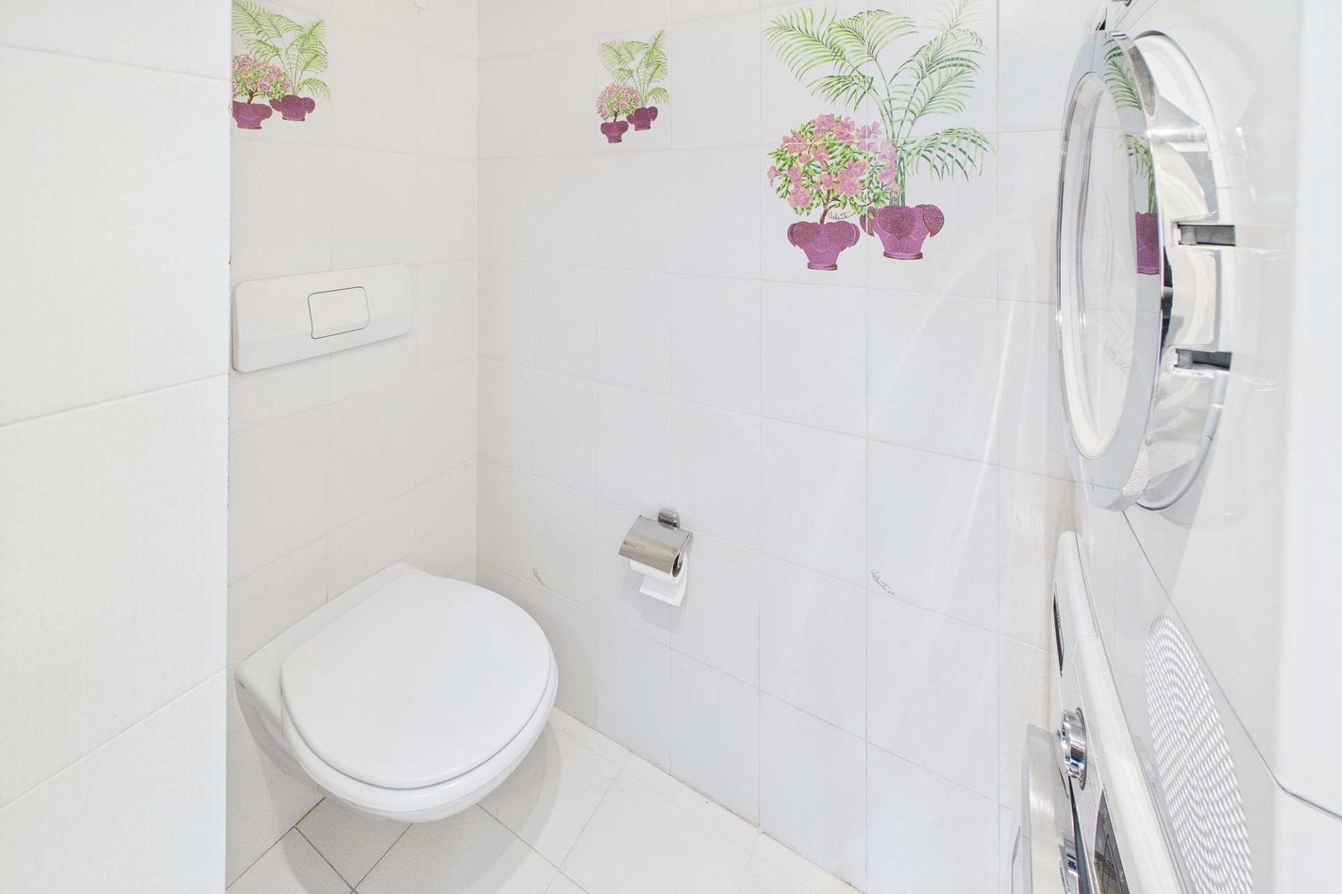 Kleines weißes WC mit dekorierten Fliesen