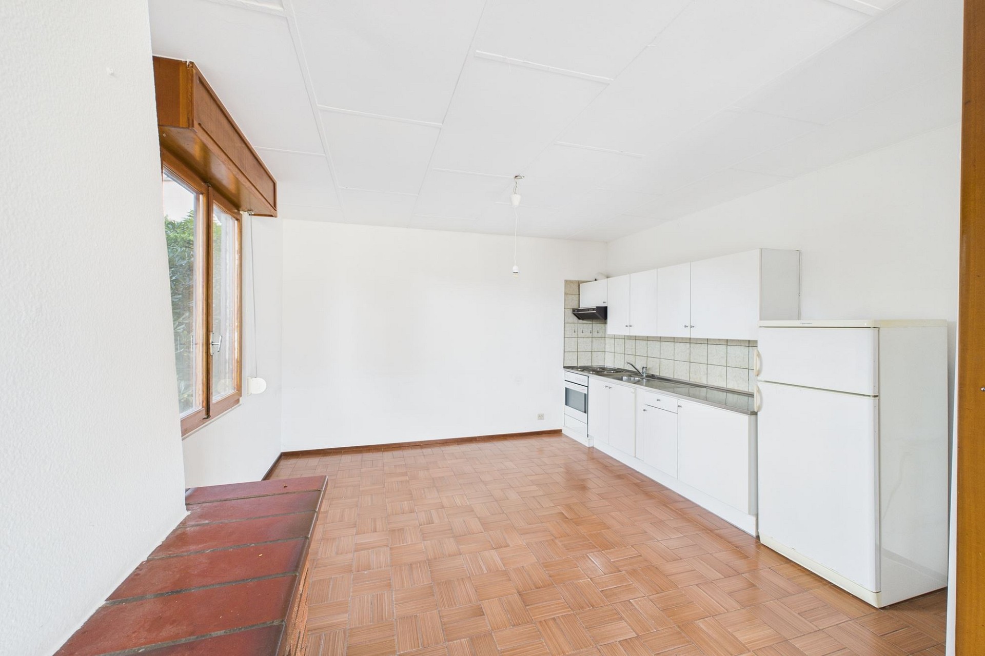Helle, leere Küche mit Holzfenster und Kühlschrank