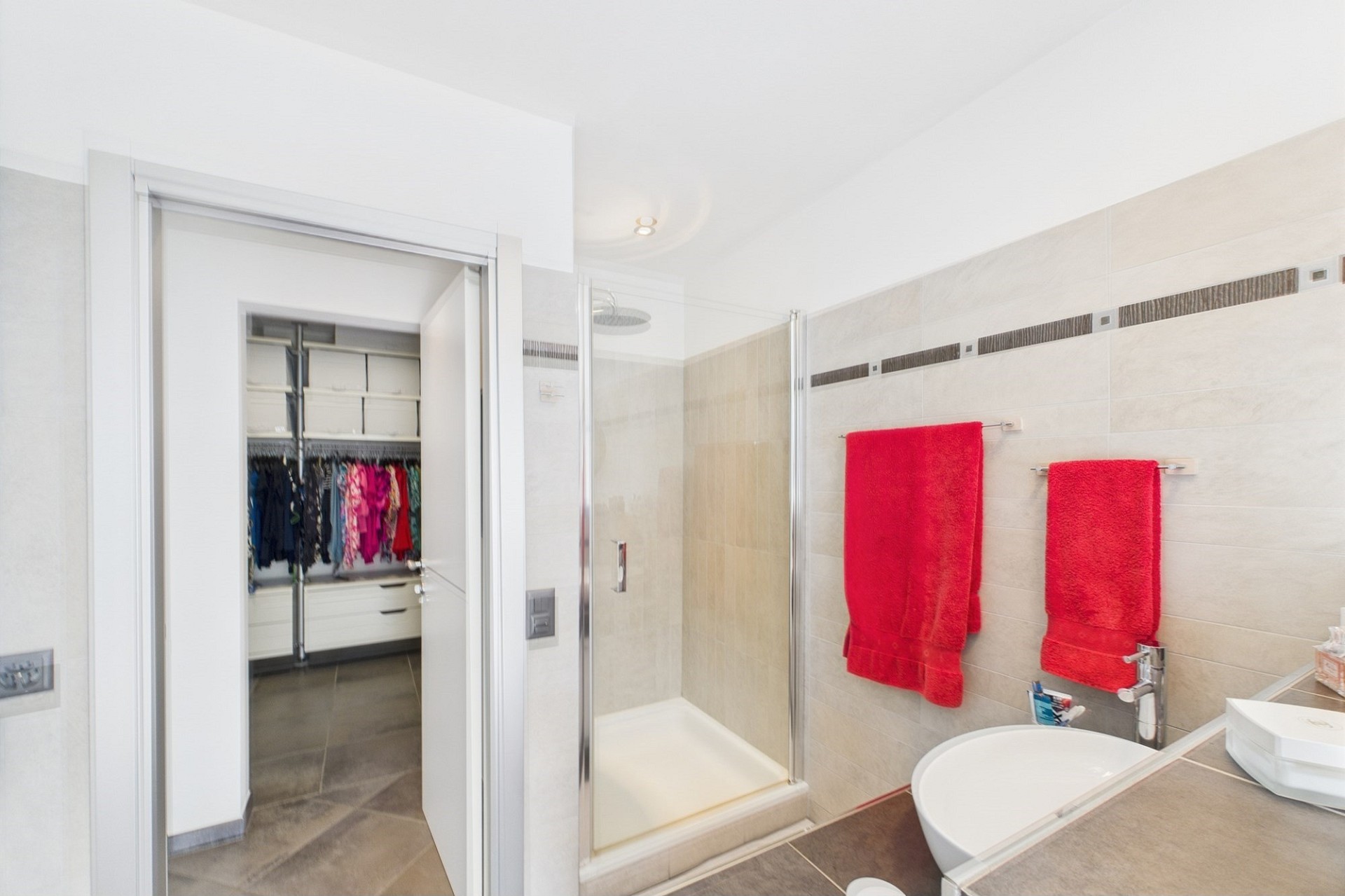 Modernes Badezimmer mit begehbarer Dusche und Ankleideblick