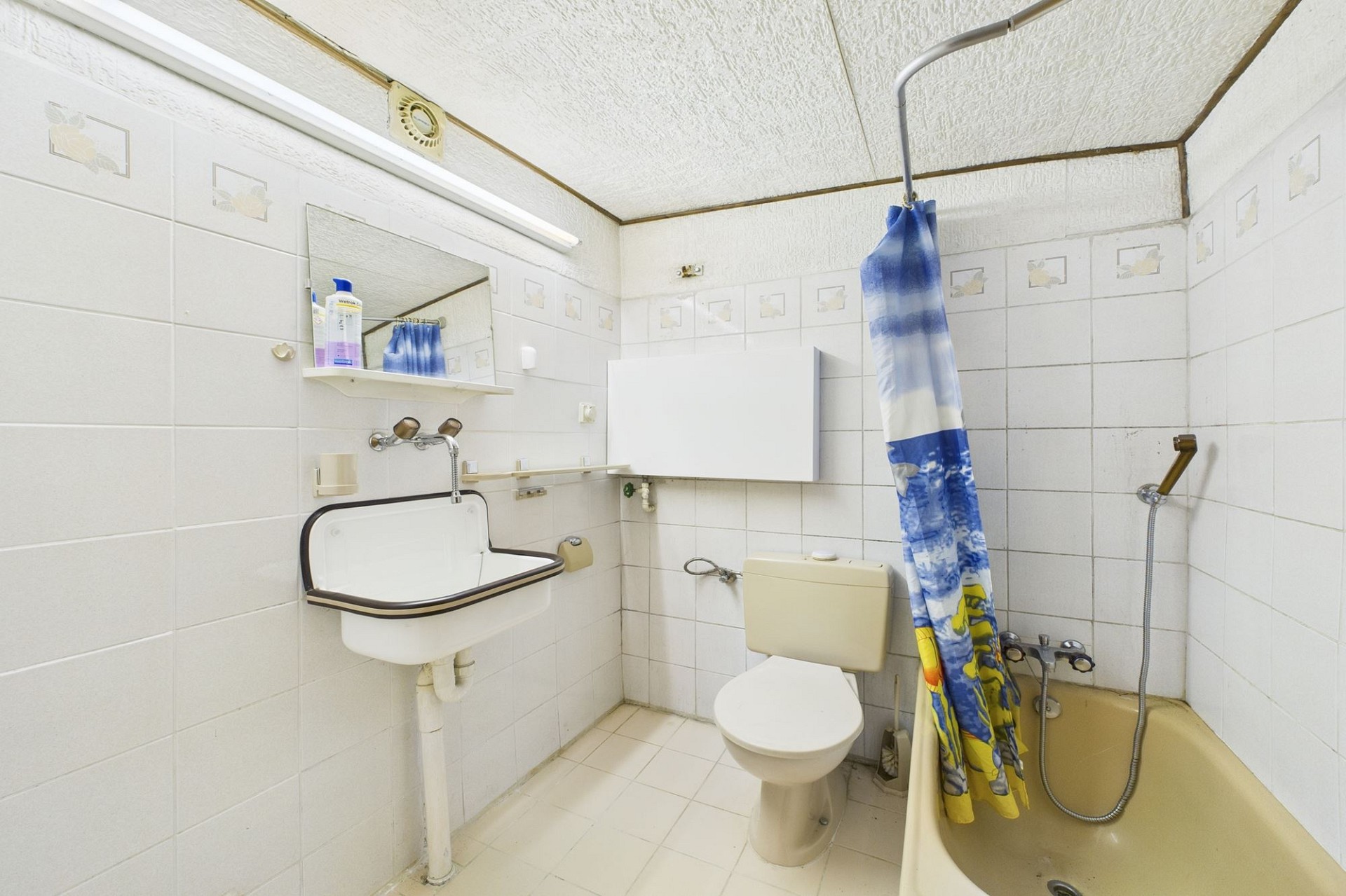 Ein einfaches Badezimmer mit Badewanne, WC und Waschbecken