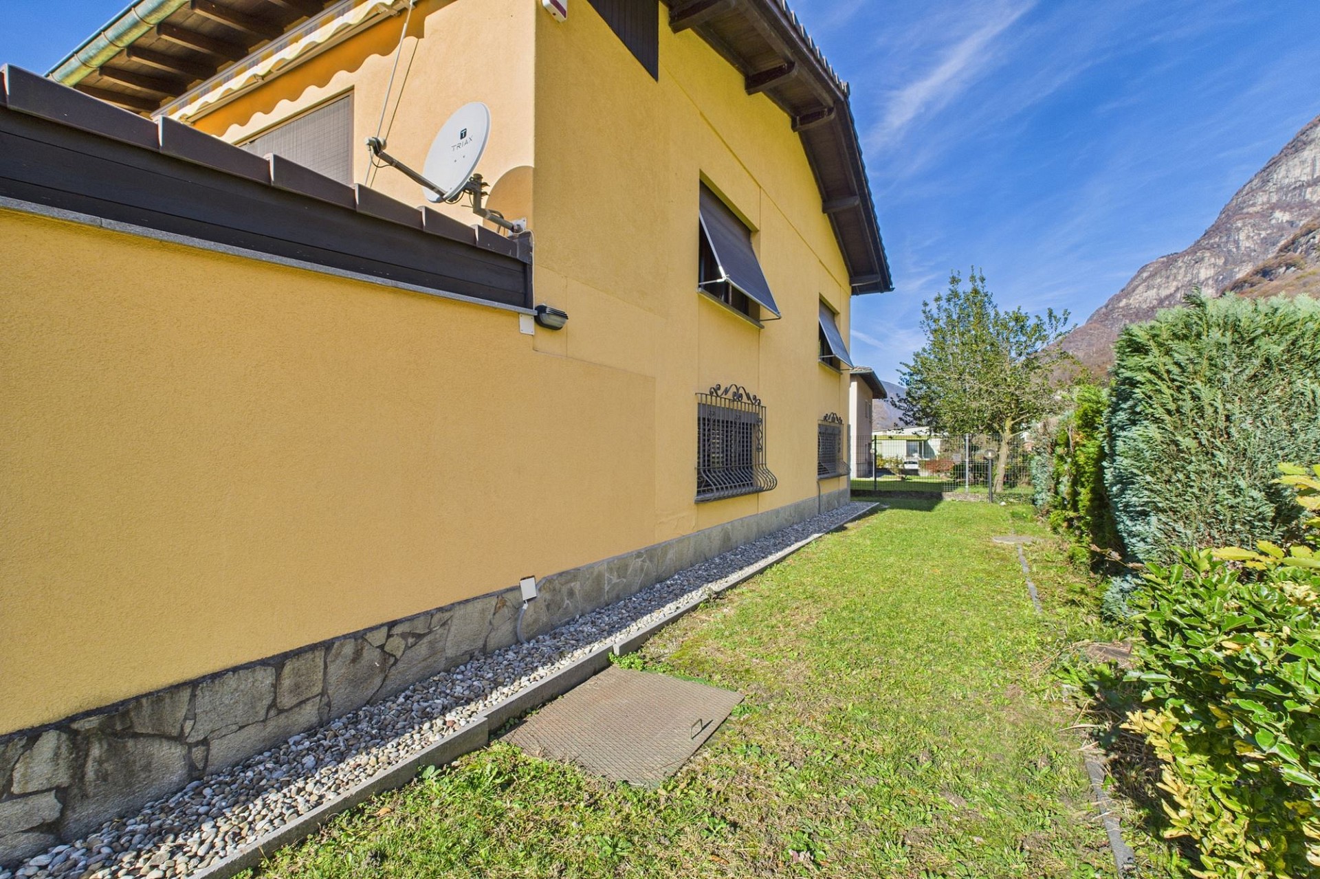 Hausaußenansicht mit Garten und Bergkulisse