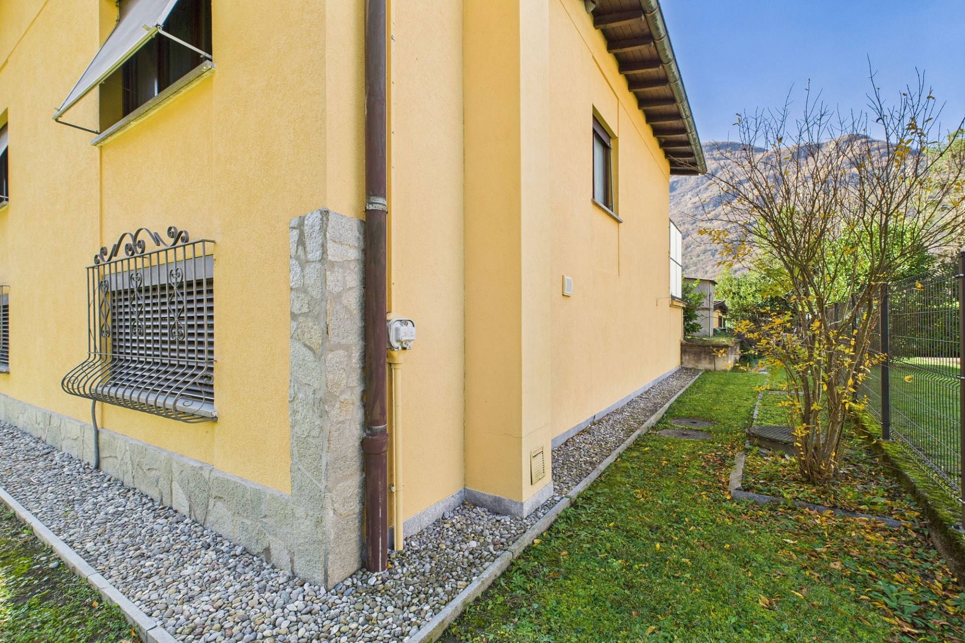 Außenansicht eines gelb verputzten Wohnhauses mit Garten