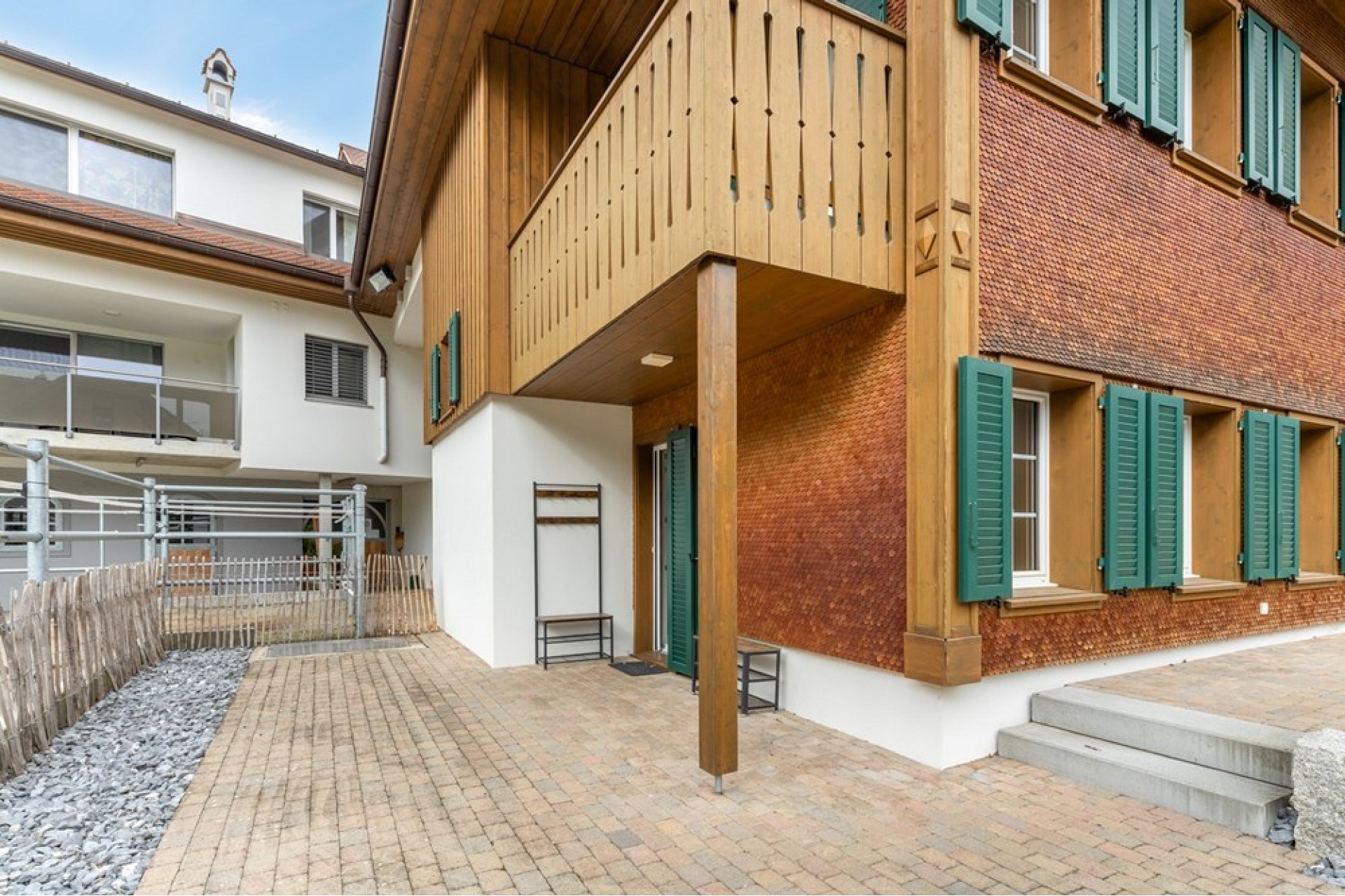 Außenansicht eines Hauses mit Holzfassade und grünen Fensterläden
