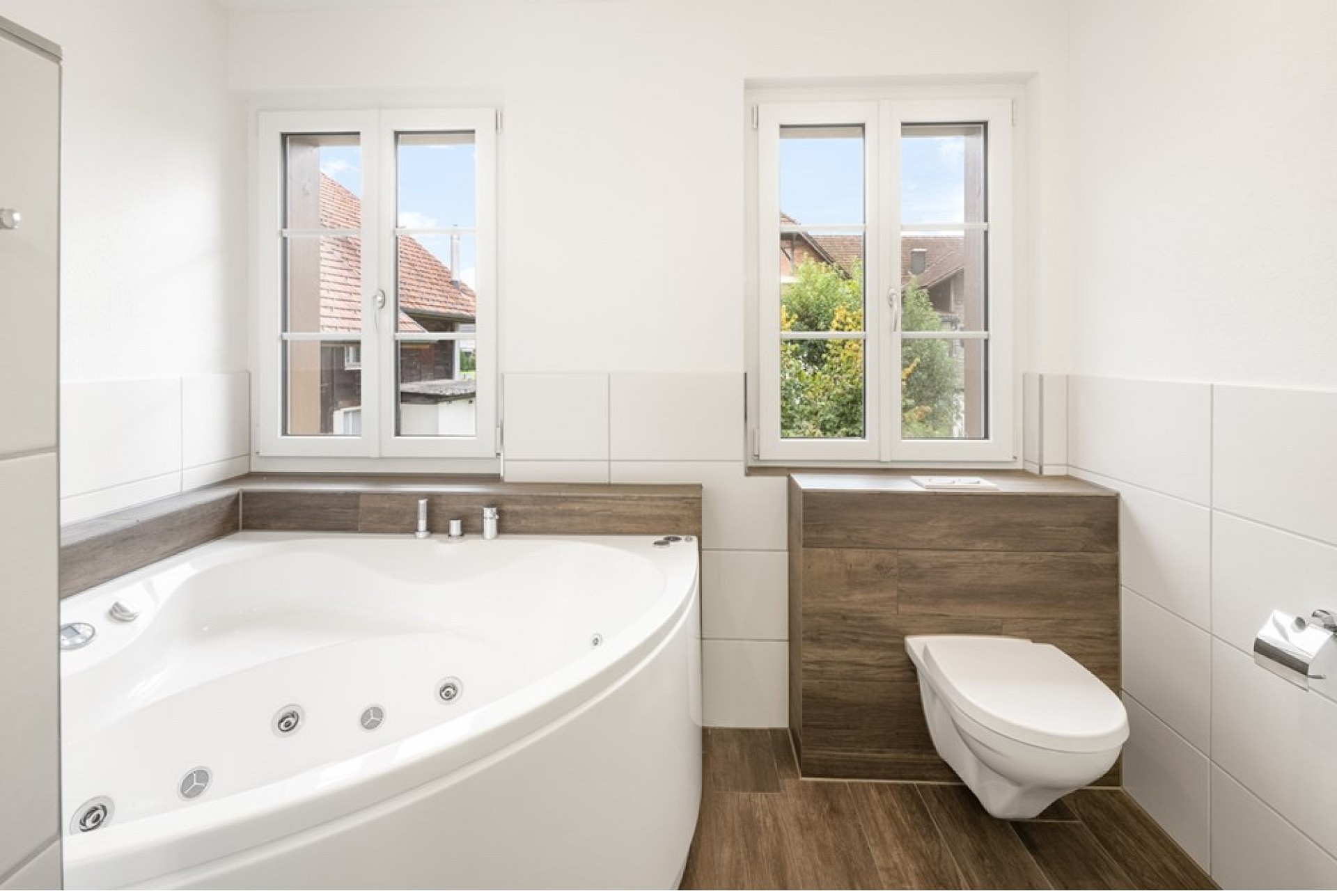 Helles Badezimmer mit Eckbadewanne und wandhängendem WC