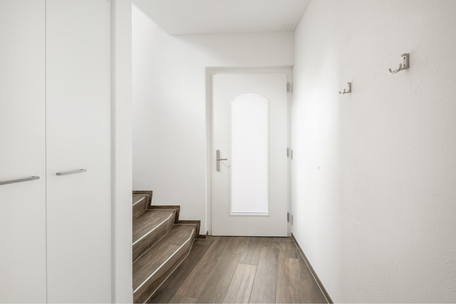 Heller Eingangsflur mit Treppe und Glastür