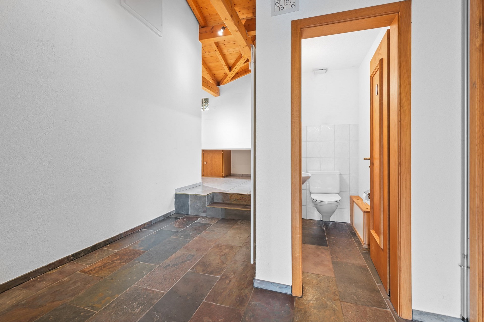 Heller Flur mit sichtbarem Badezimmer und Holzdecke