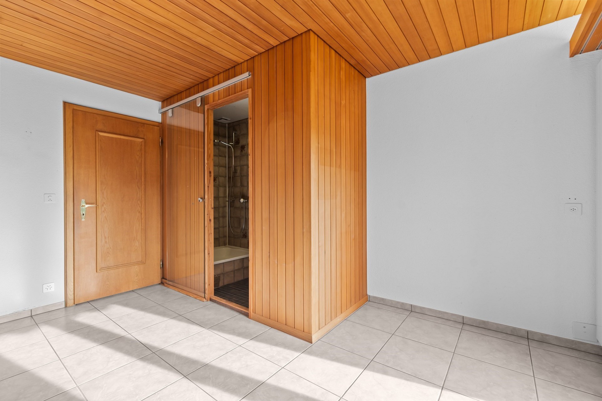 Heller Raum mit Holzverkleidung und angrenzender Dusche