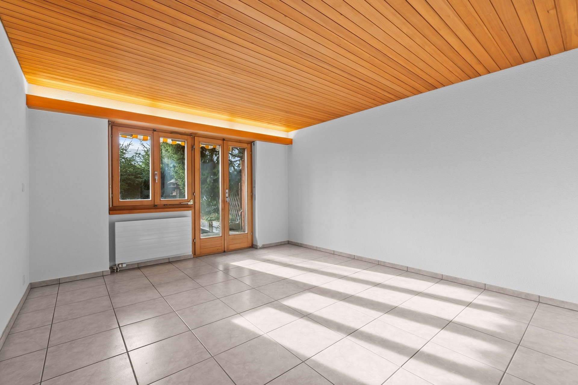 Heller leerer Raum mit Holzdecke und Fliesenboden